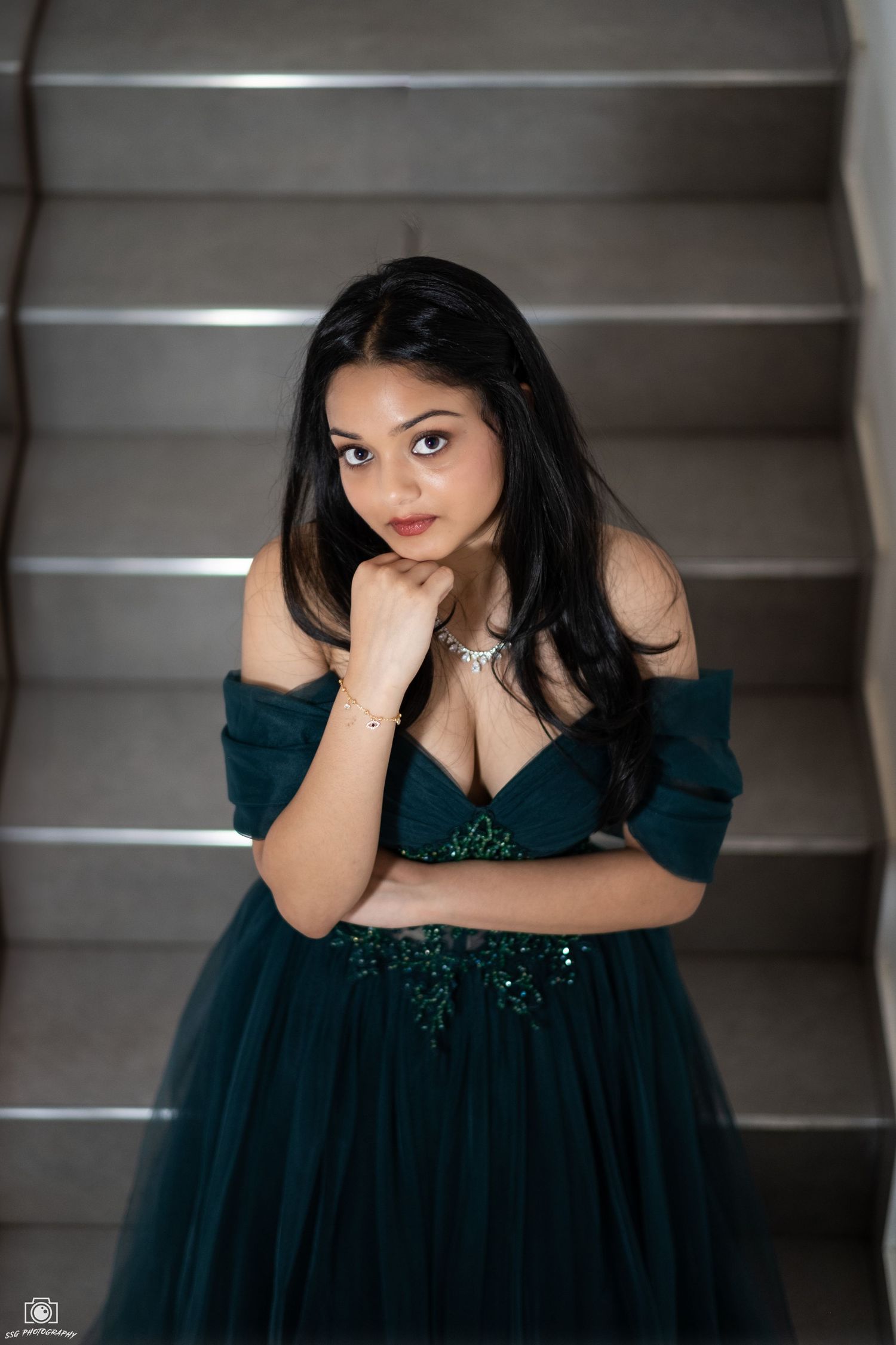 Dramatic staircase photoshoot featuring a dark teal evening gown with sequin details.