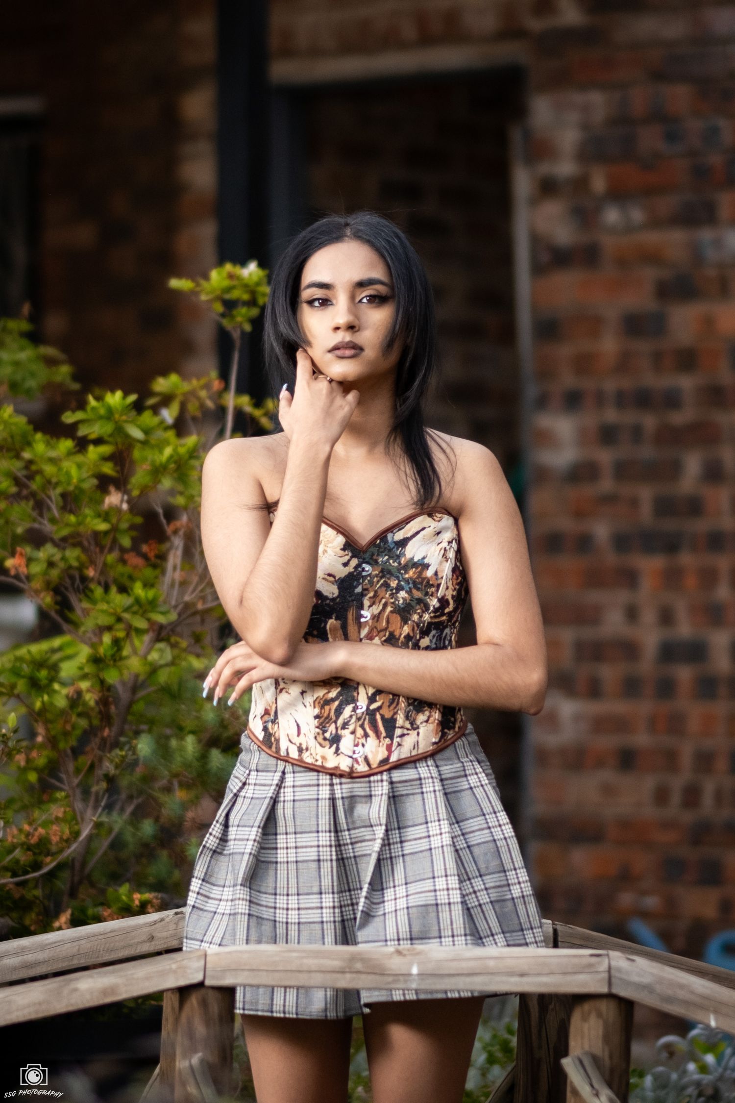 A portrait session on a wooden bench against a rustic brick wall background.