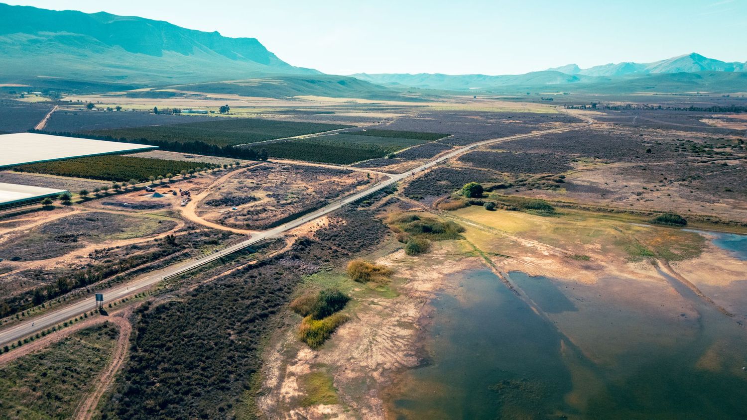 Aerial view of desert highway intersection with mountains and farmland.