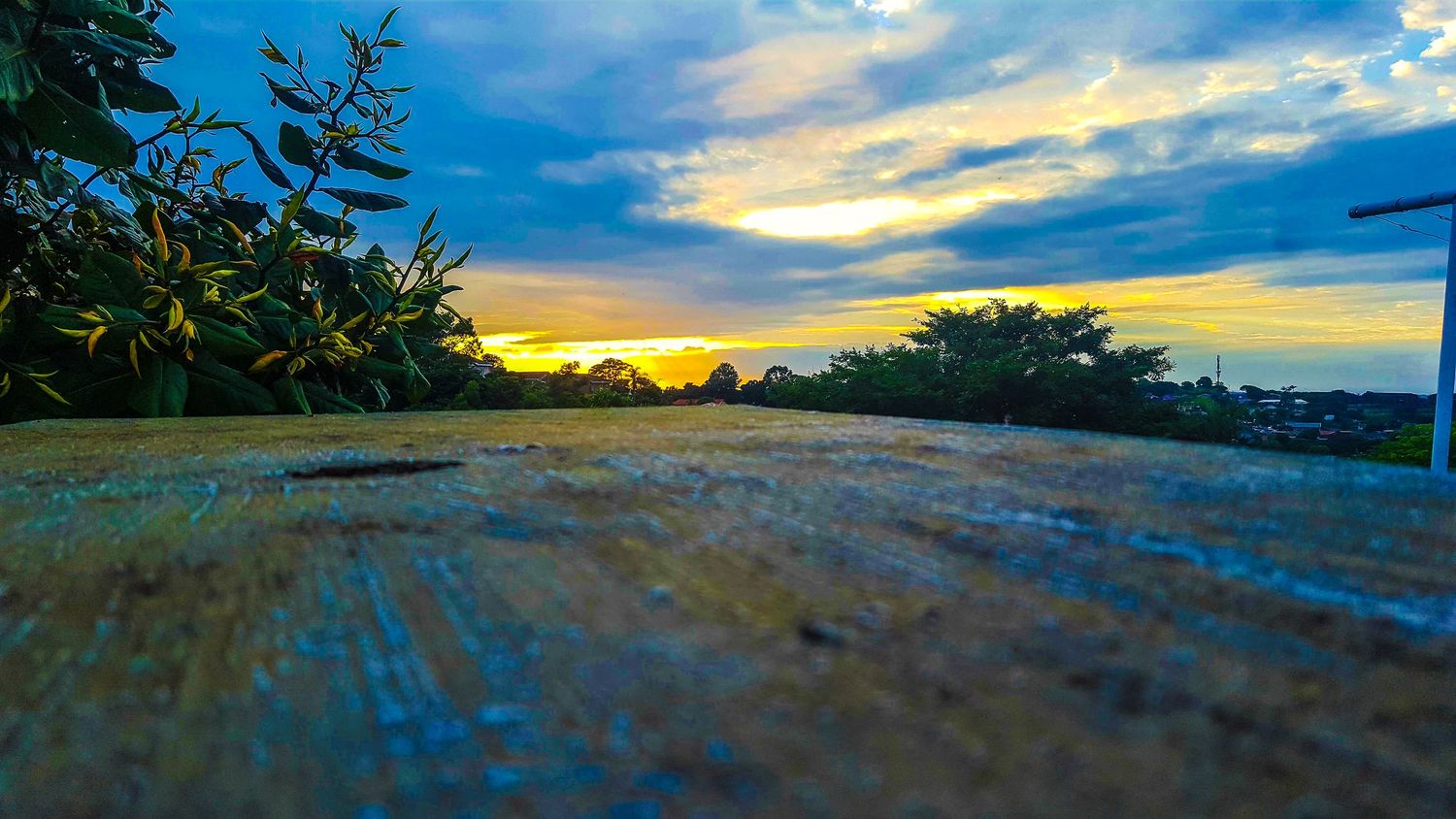 A panoramic sunset view over a tropical beach with palm trees silhouetted against a dramatic orange and blue sky.