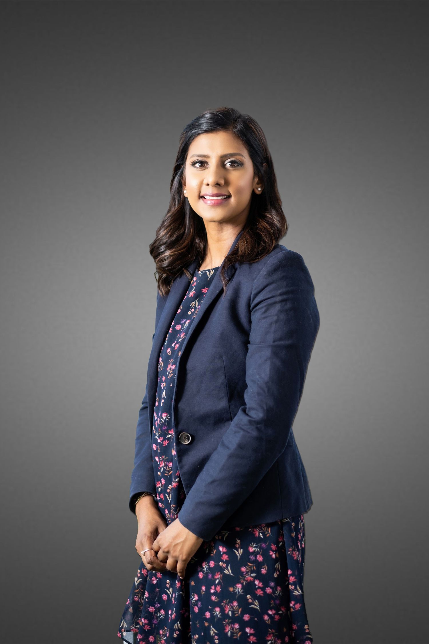 Professional studio portrait series against grey background featuring navy blazer and floral dress.