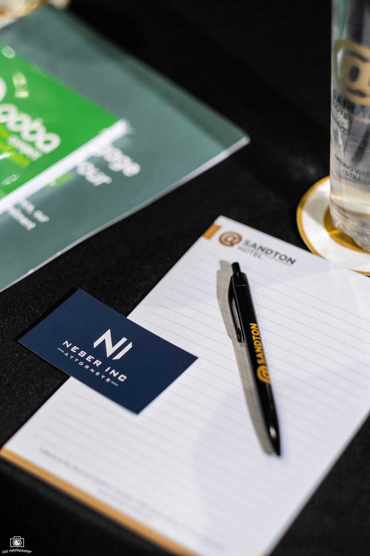 Professional notepads and pens arranged on a dark surface with business cards.