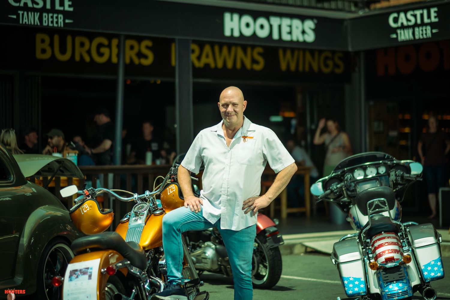 Restaurant storefront with motorcycles parked outside showing signage for burgers, prawns and wings.