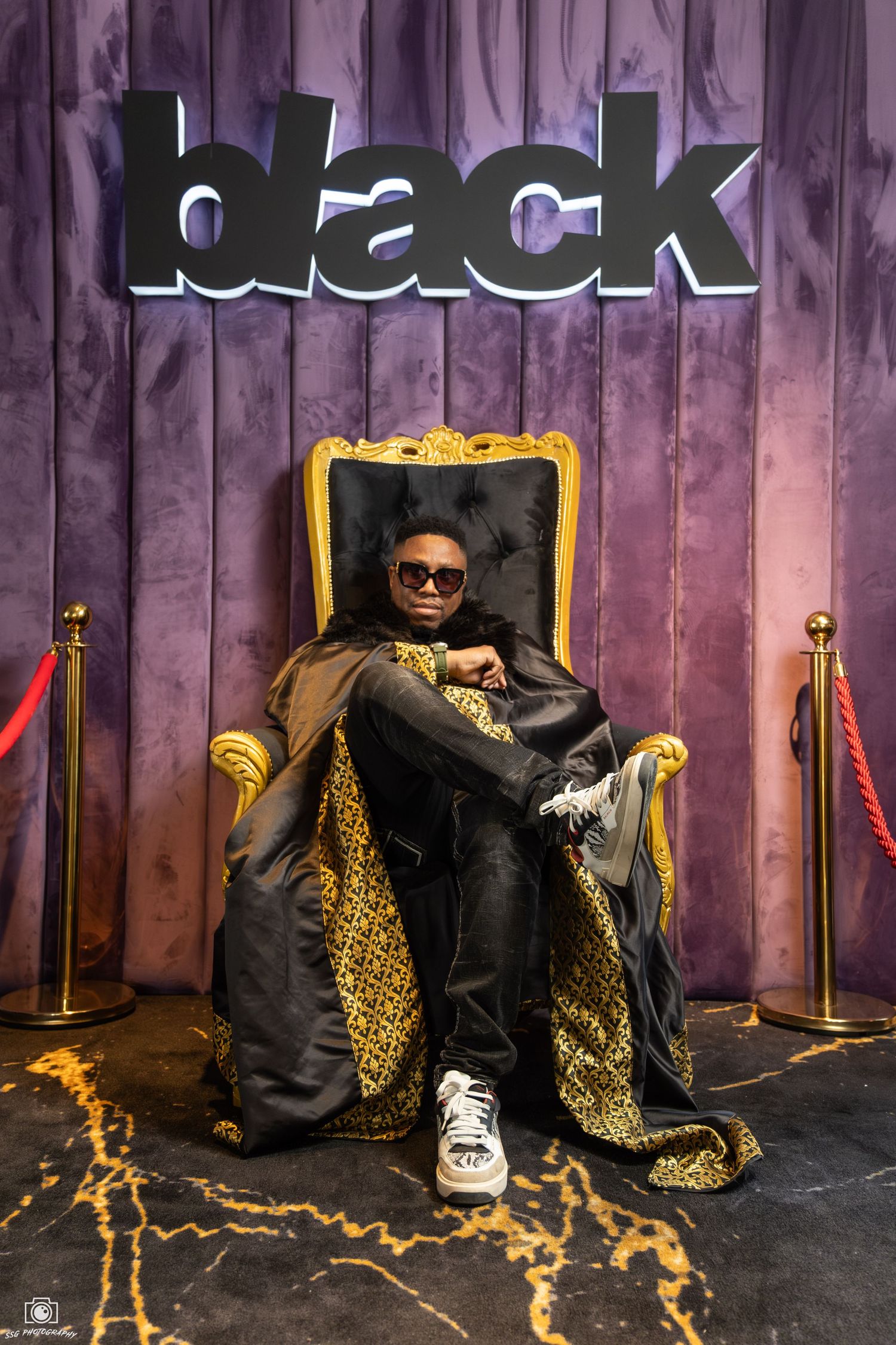 Ornate throne chair with black and gold leopard print fabric on a dark stage.