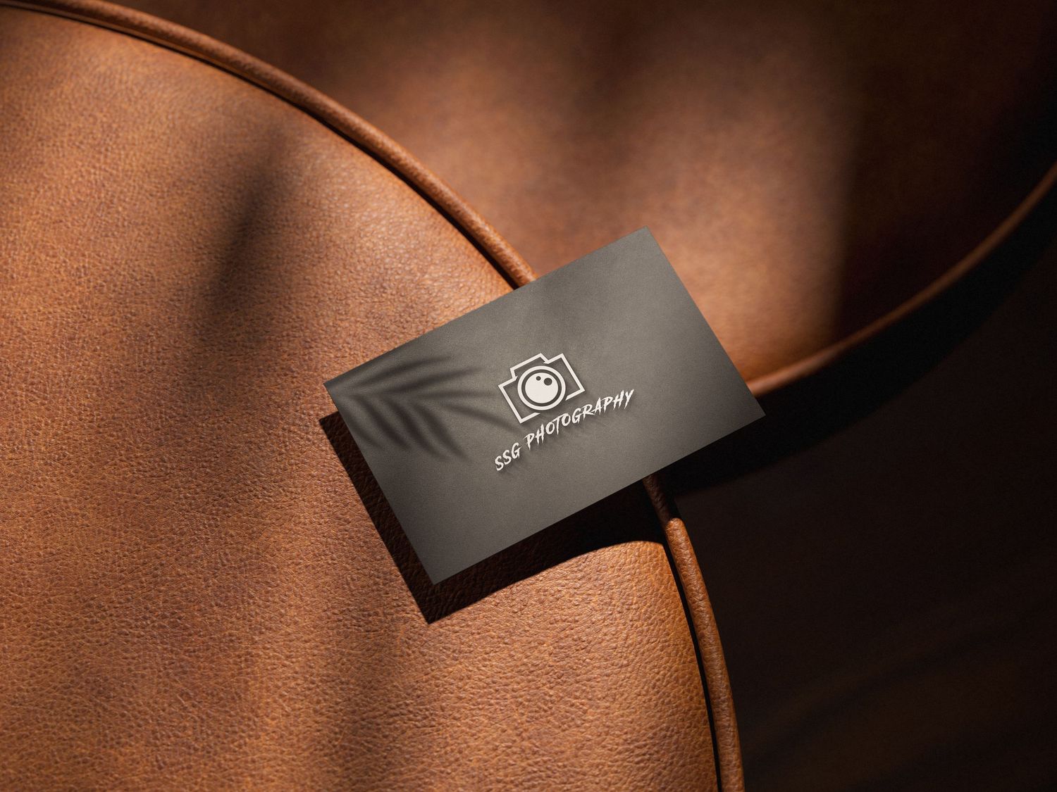 Dark business cards arranged diagonally on brown leather background.