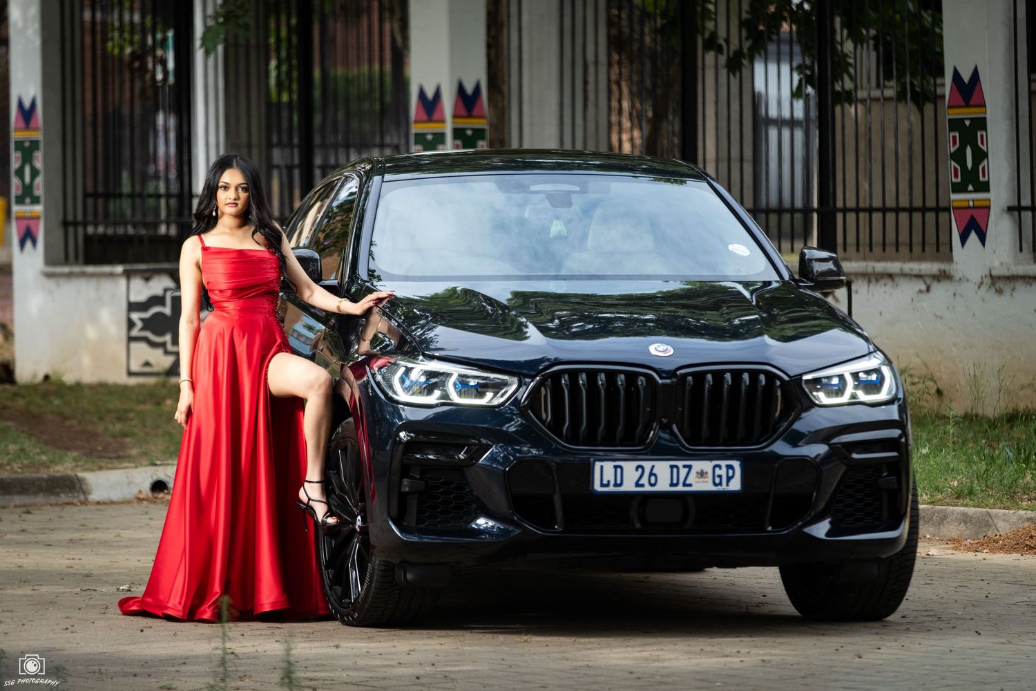 Luxury car photoshoot featuring a red gown against a black BMW.