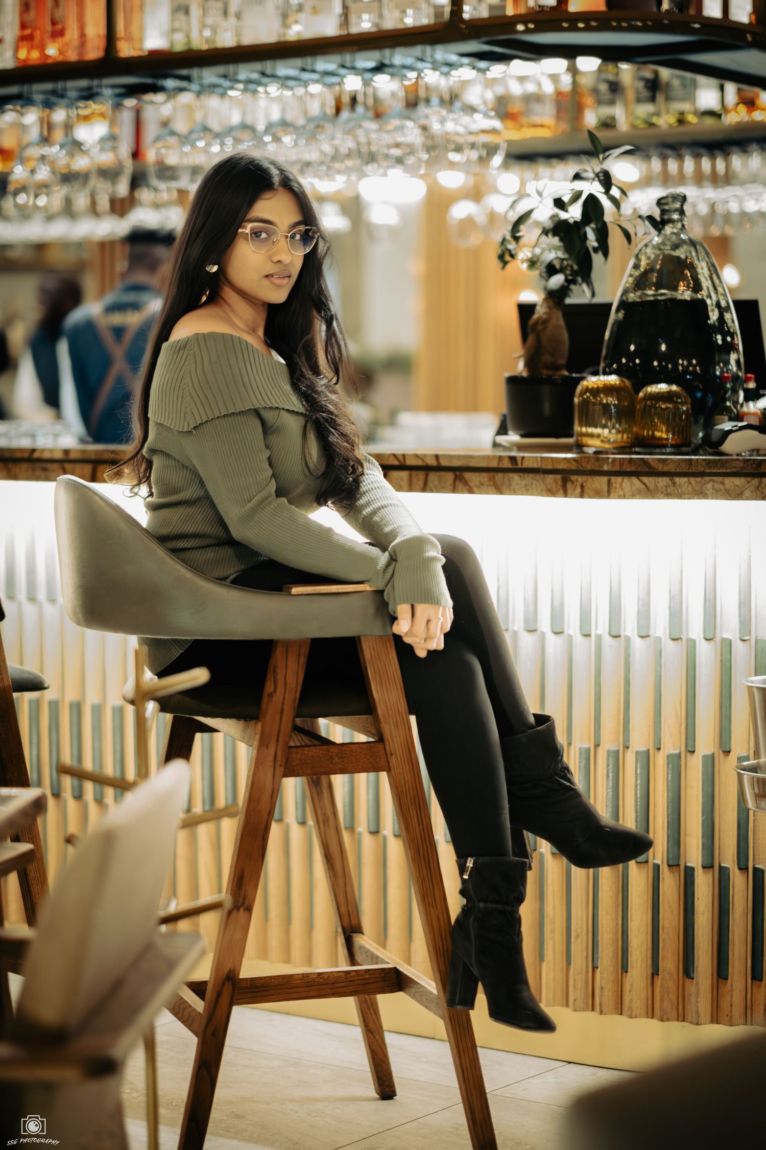 Lifestyle portraits at a modern bar with wooden stools and ambient lighting.