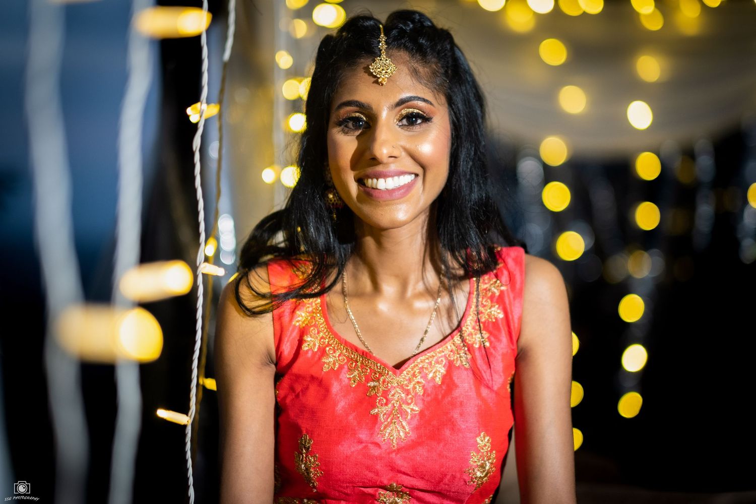 Close-up portrait in red dress with sparkling bokeh lights in background.