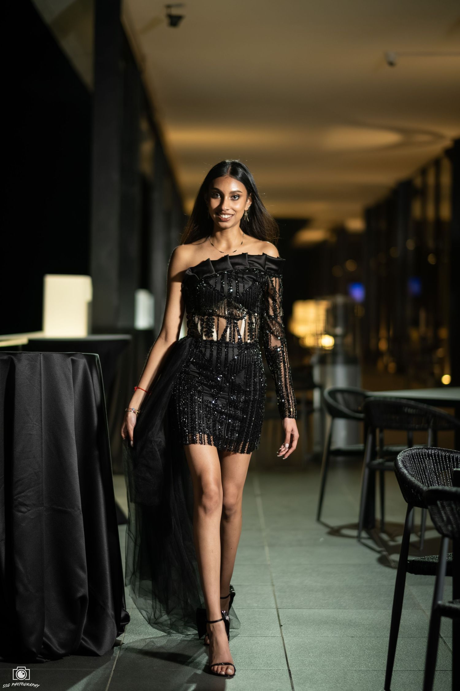 Evening photoshoot in a modern venue with black tablecloths and ambient lighting.