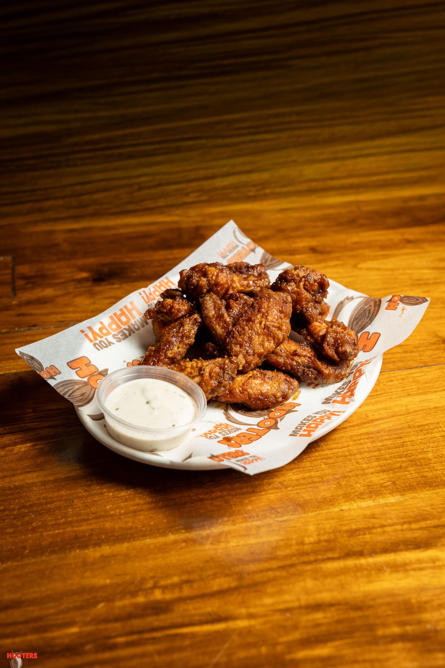 Crispy fried chicken wings with dipping sauce on wooden table.