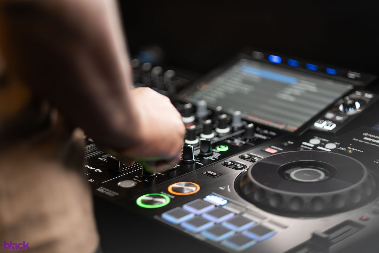 Close-up shot of DJ controller with finger adjusting knobs and buttons.