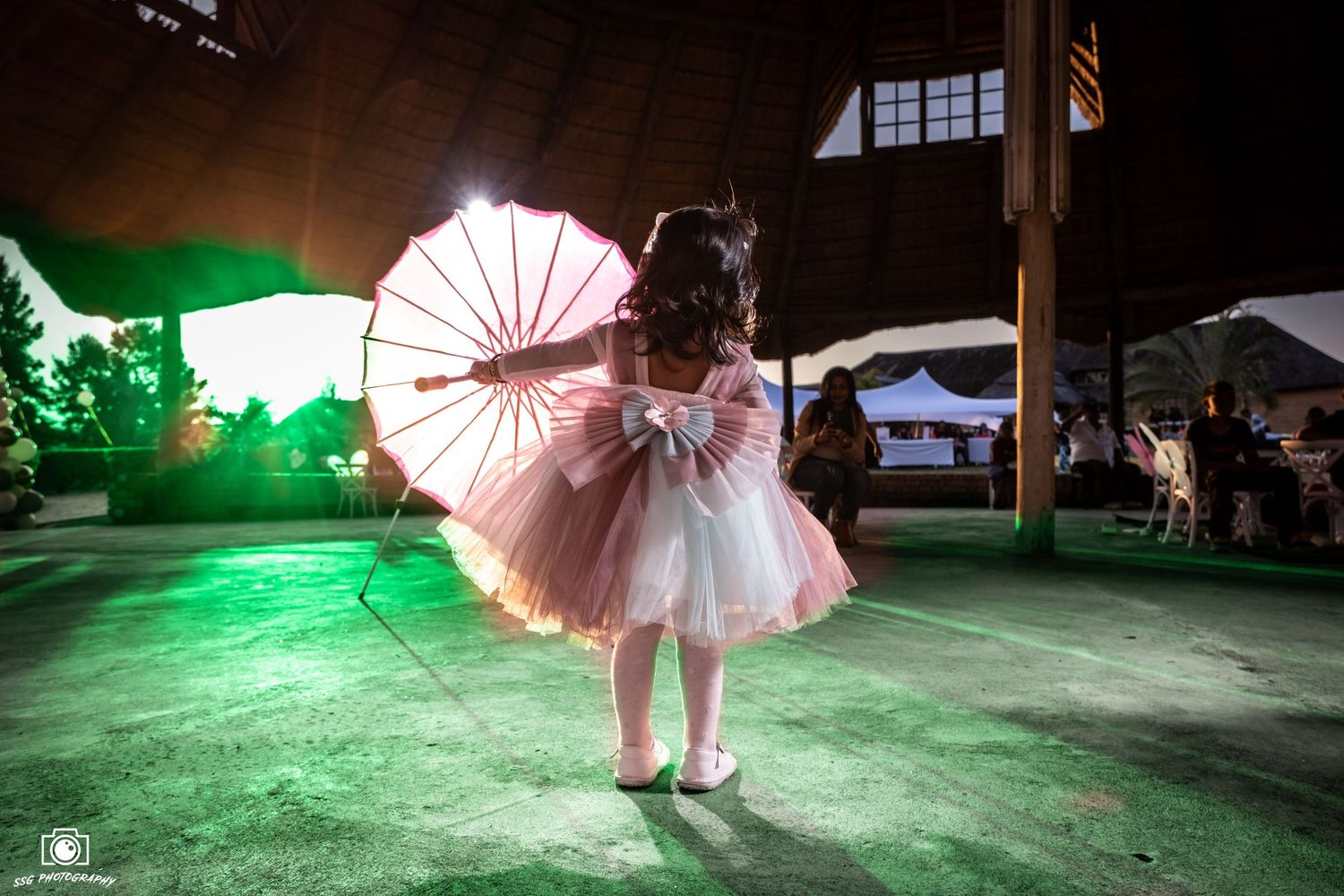 Capturing candid moments at a Gauteng wedding: A child in a pink and white dress with a lit-up umbrella, photographed by SSG Photography.