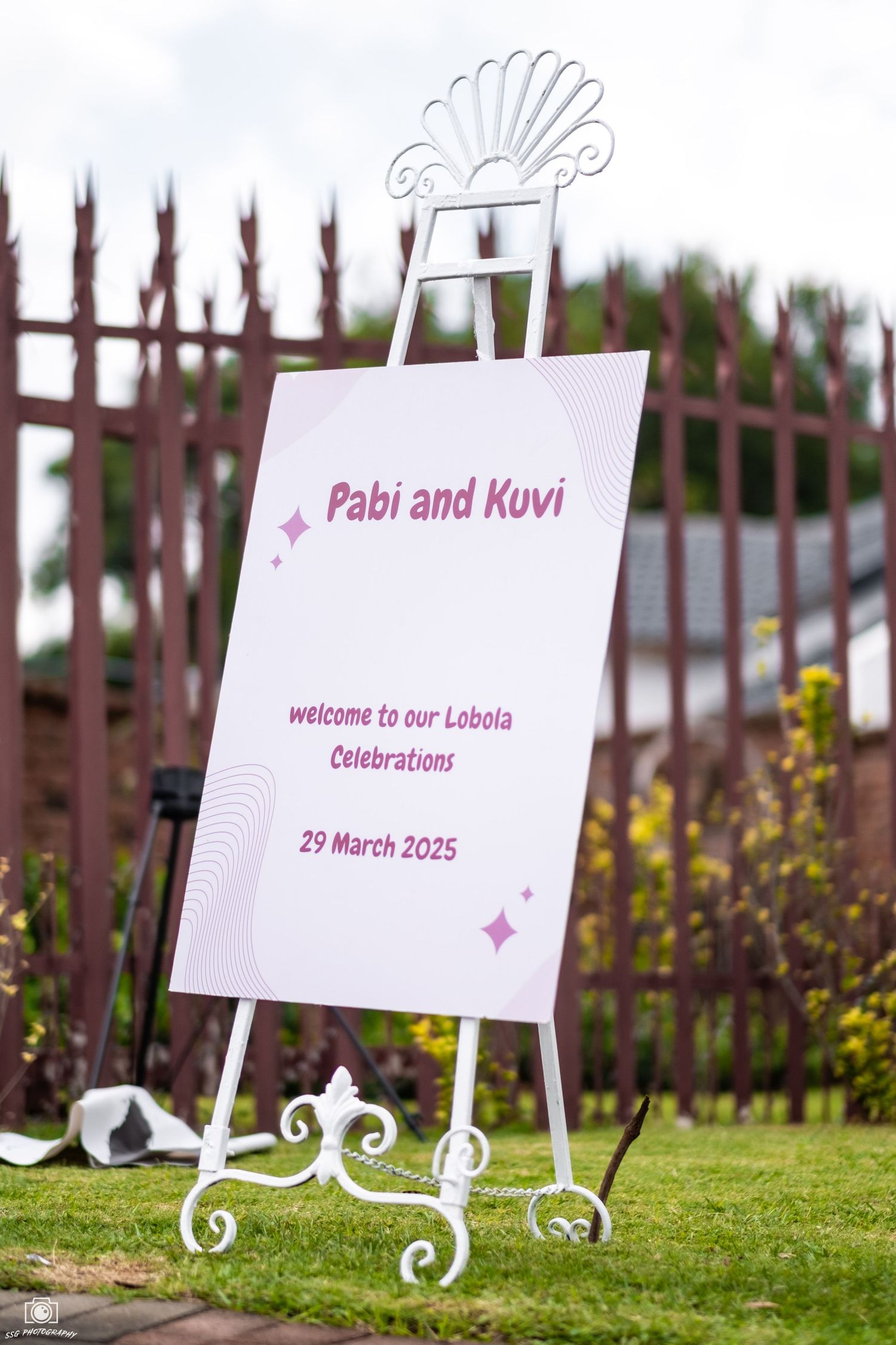 Row of decorative white signs with ornate text displayed on a grassy lawn.