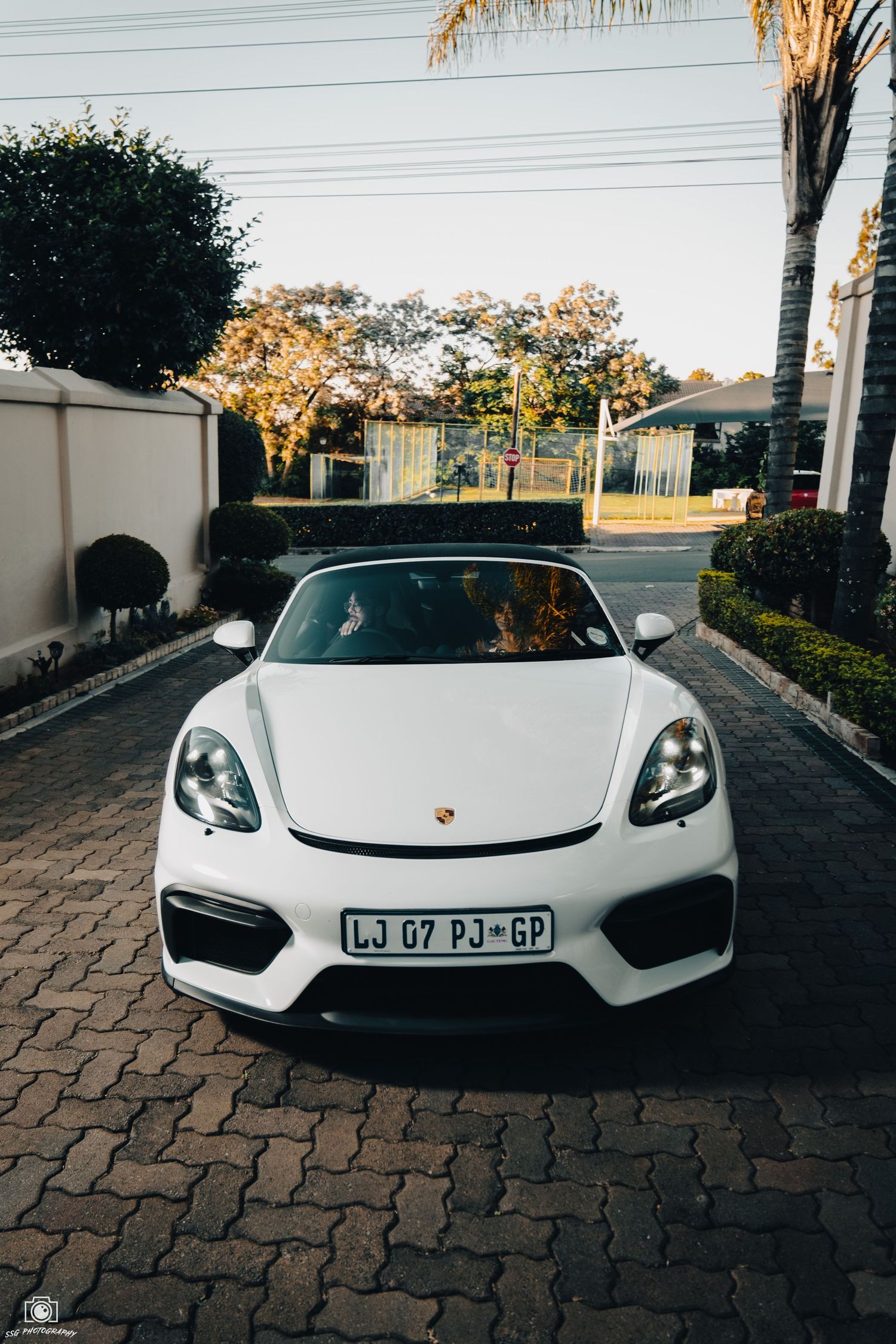Front view of a white Porsche 918 Spyder on cobblestone driveway.