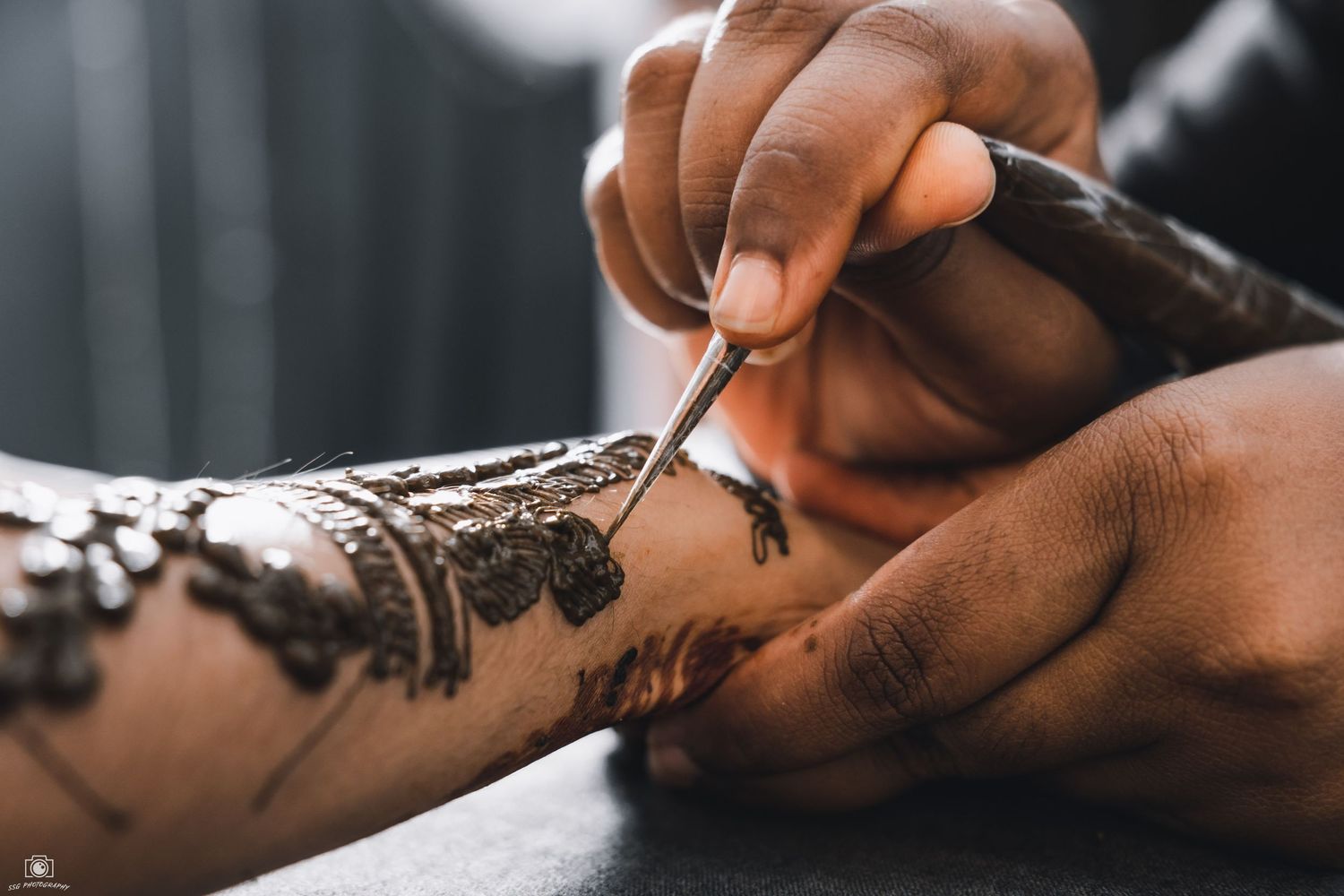 Close-up shot of hands applying intricate henna designs.