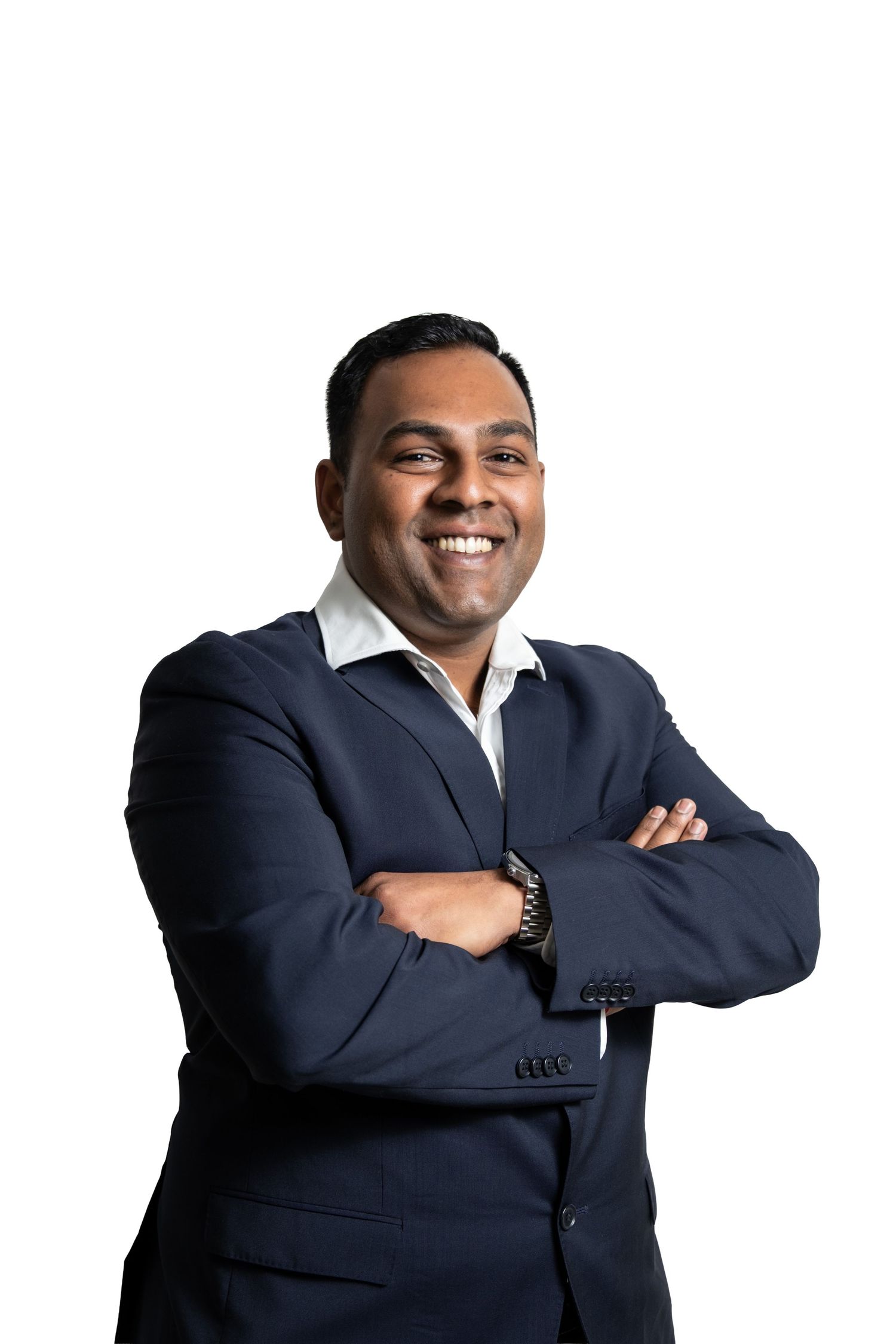 Business professional in navy suit poses with crossed arms against light background.