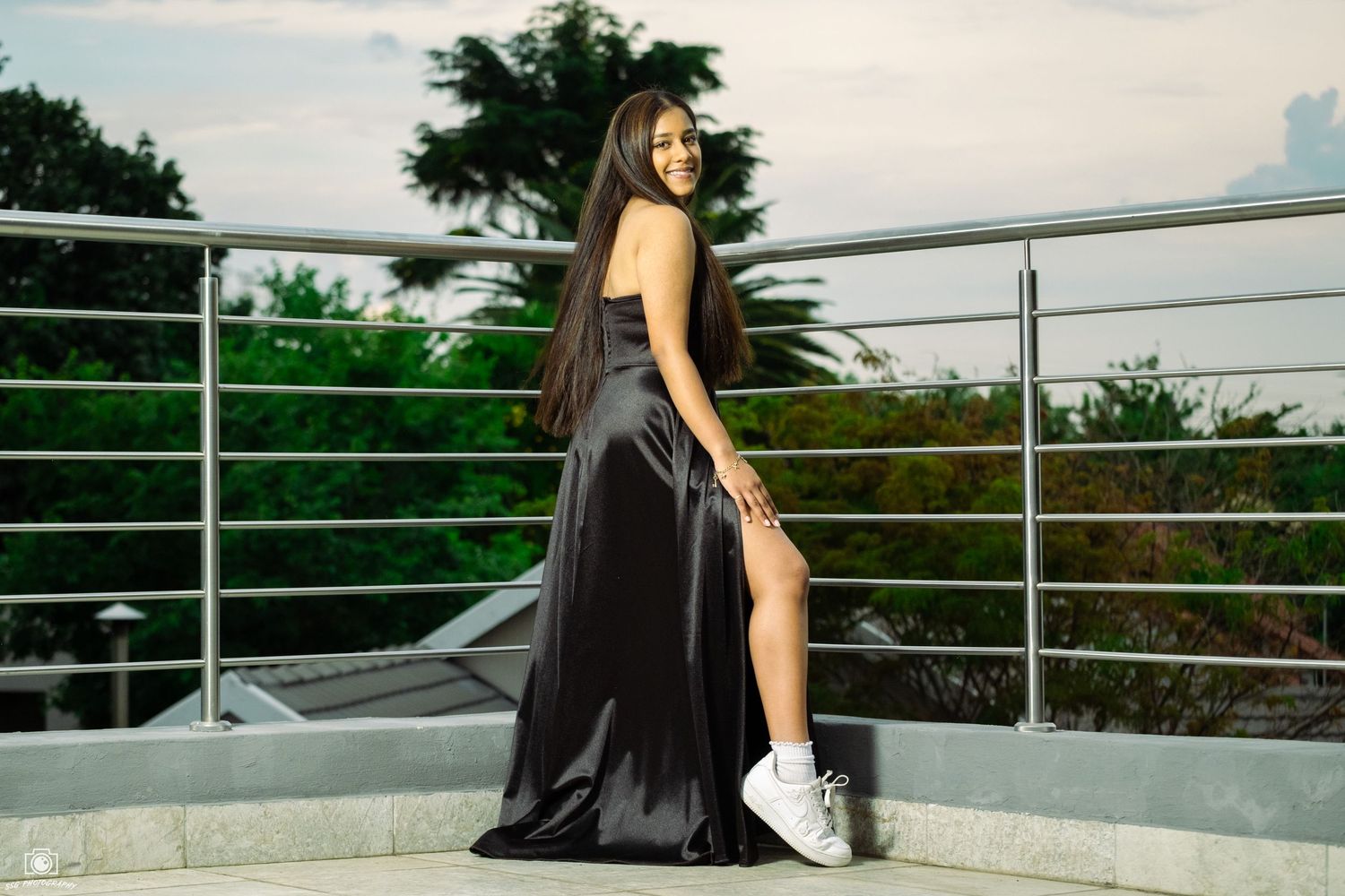 Elegant photoshoot on modern balcony with city backdrop.
