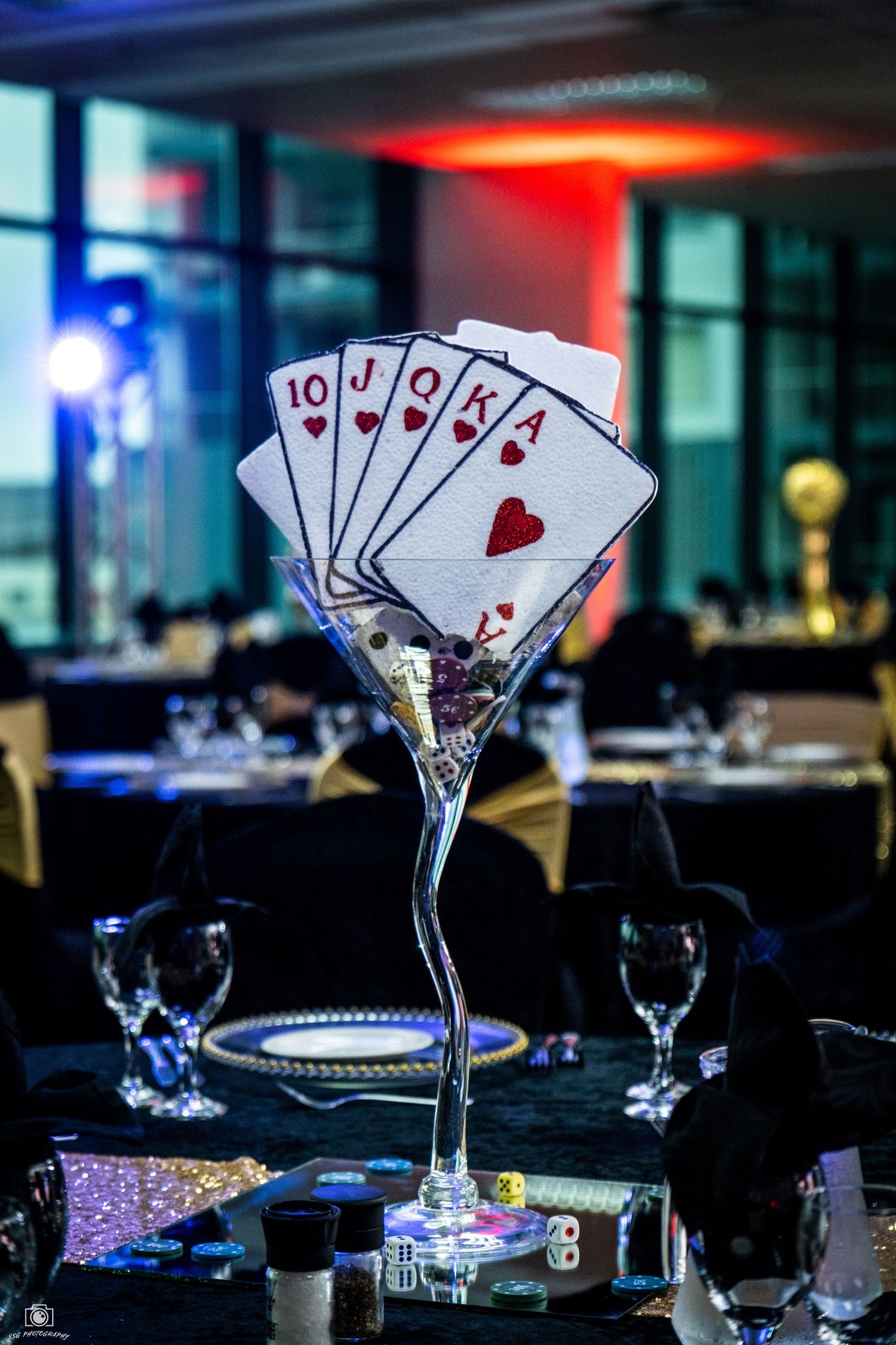 Playing cards arranged in martini glasses as casino-themed party decorations with dramatic lighting.