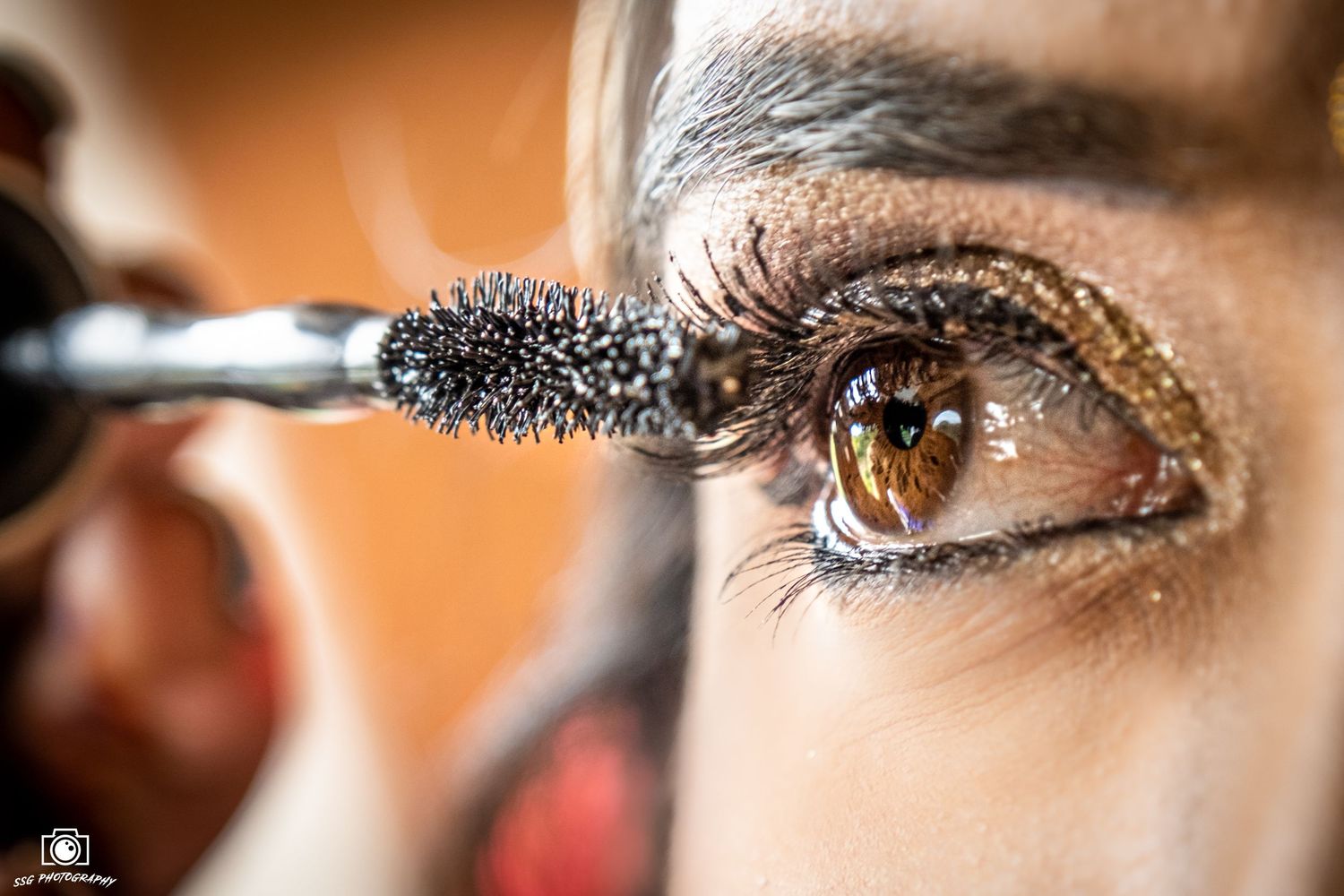 Extreme close-up of eye makeup application with mascara brush.