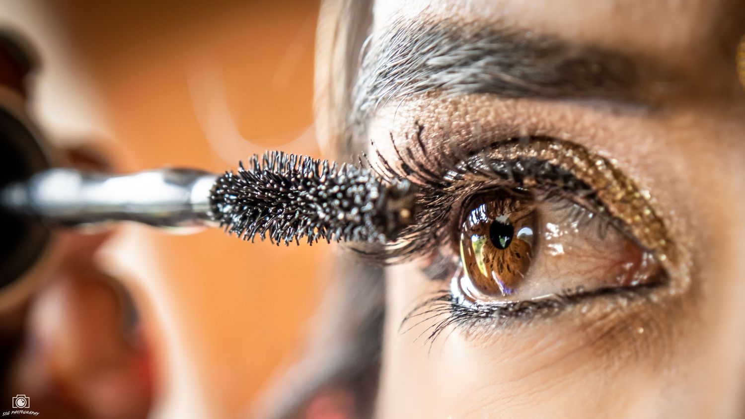 Extreme close-up of mascara being applied to eyelashes.