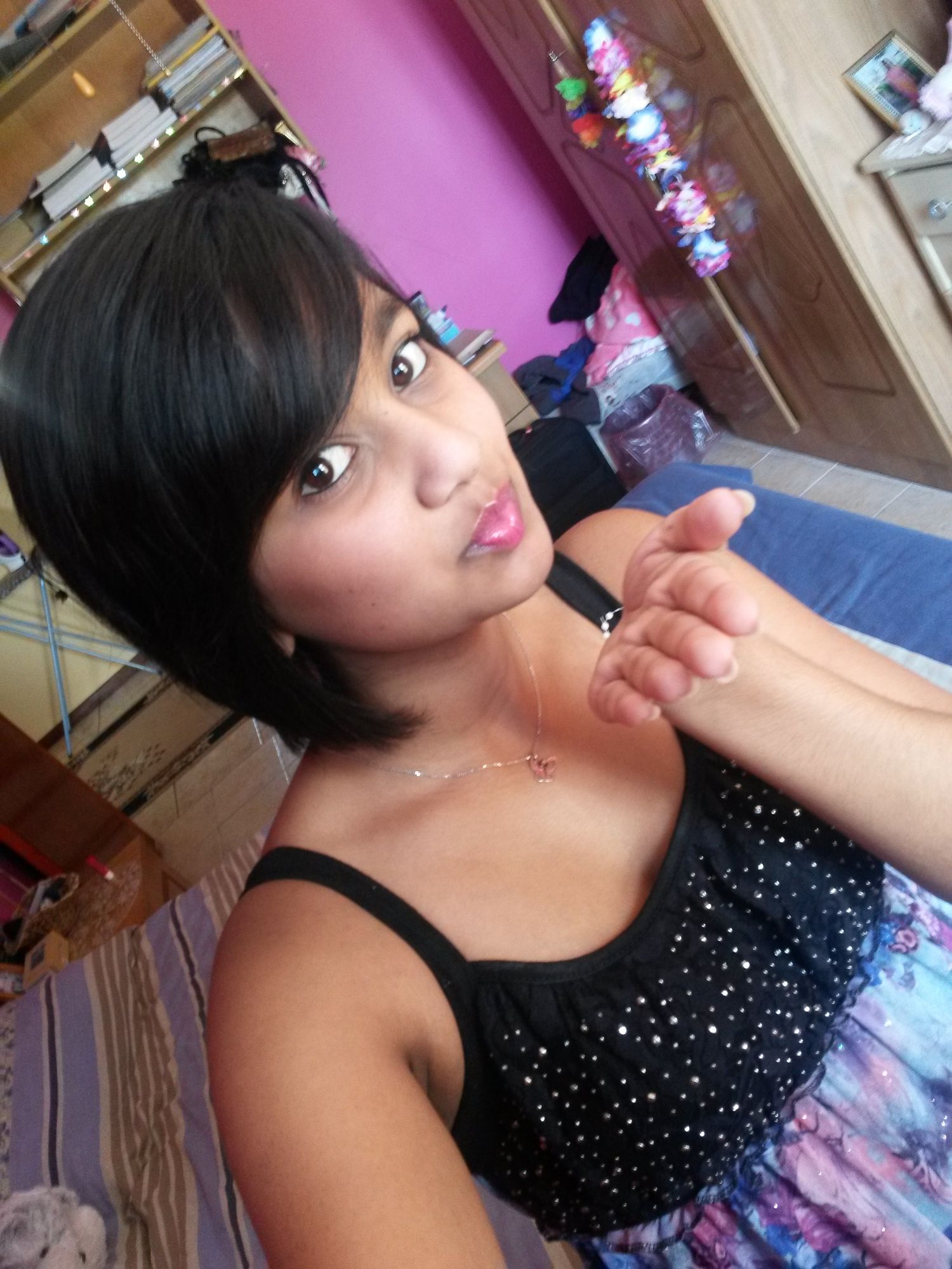 A person in a sparkly black top poses for a series of selfie photos with dramatic lighting and pink background.
