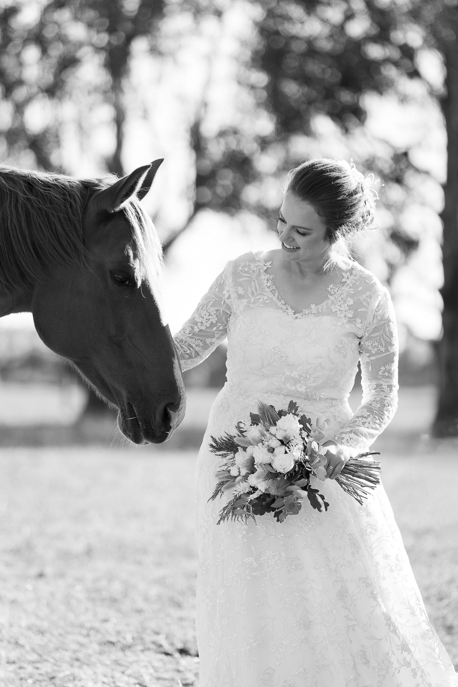 Black and white photos of bride in lace dress with horse in rustic outdoor setting.