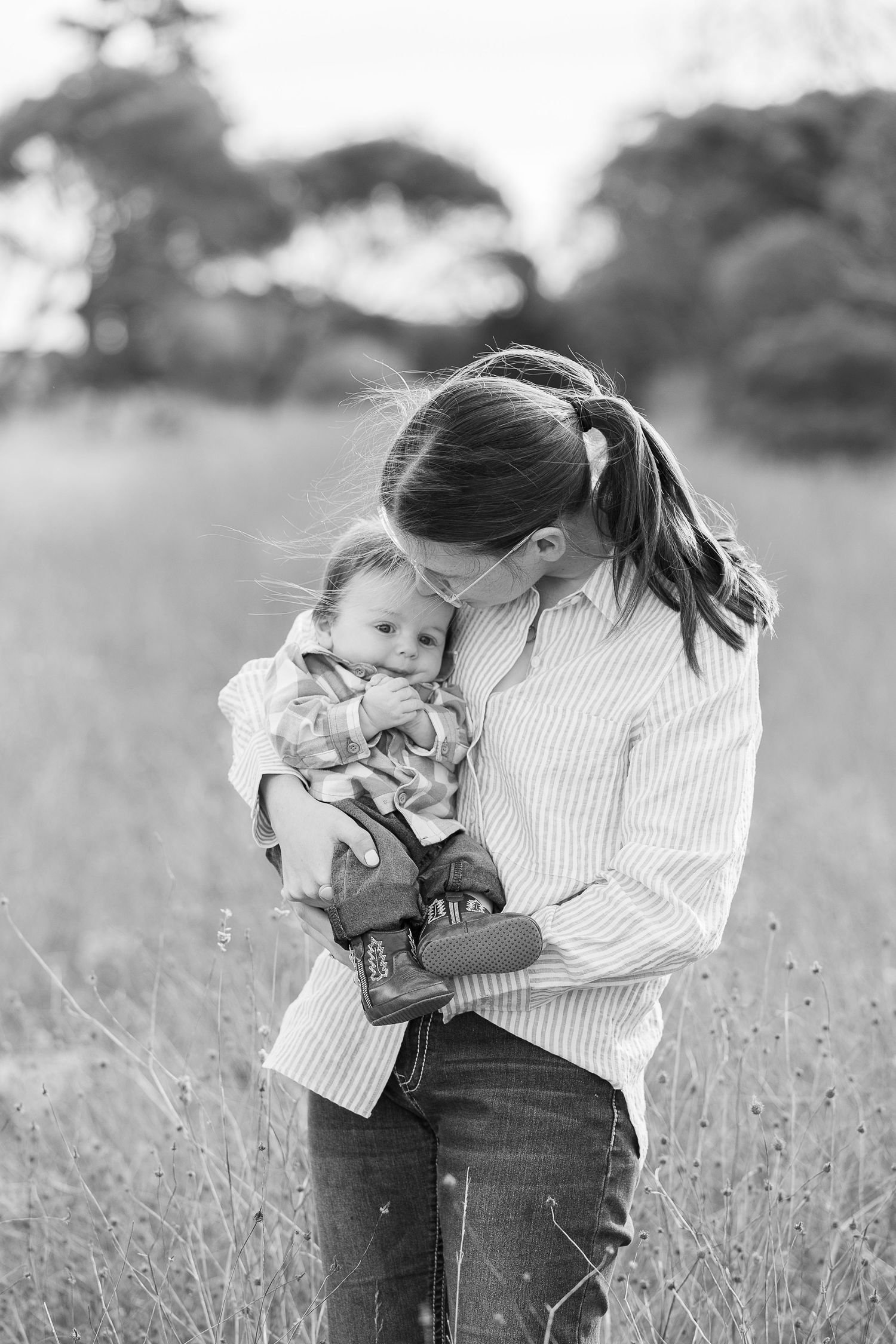 Black and white portraits showing tender moments between parent and child in a meadow.