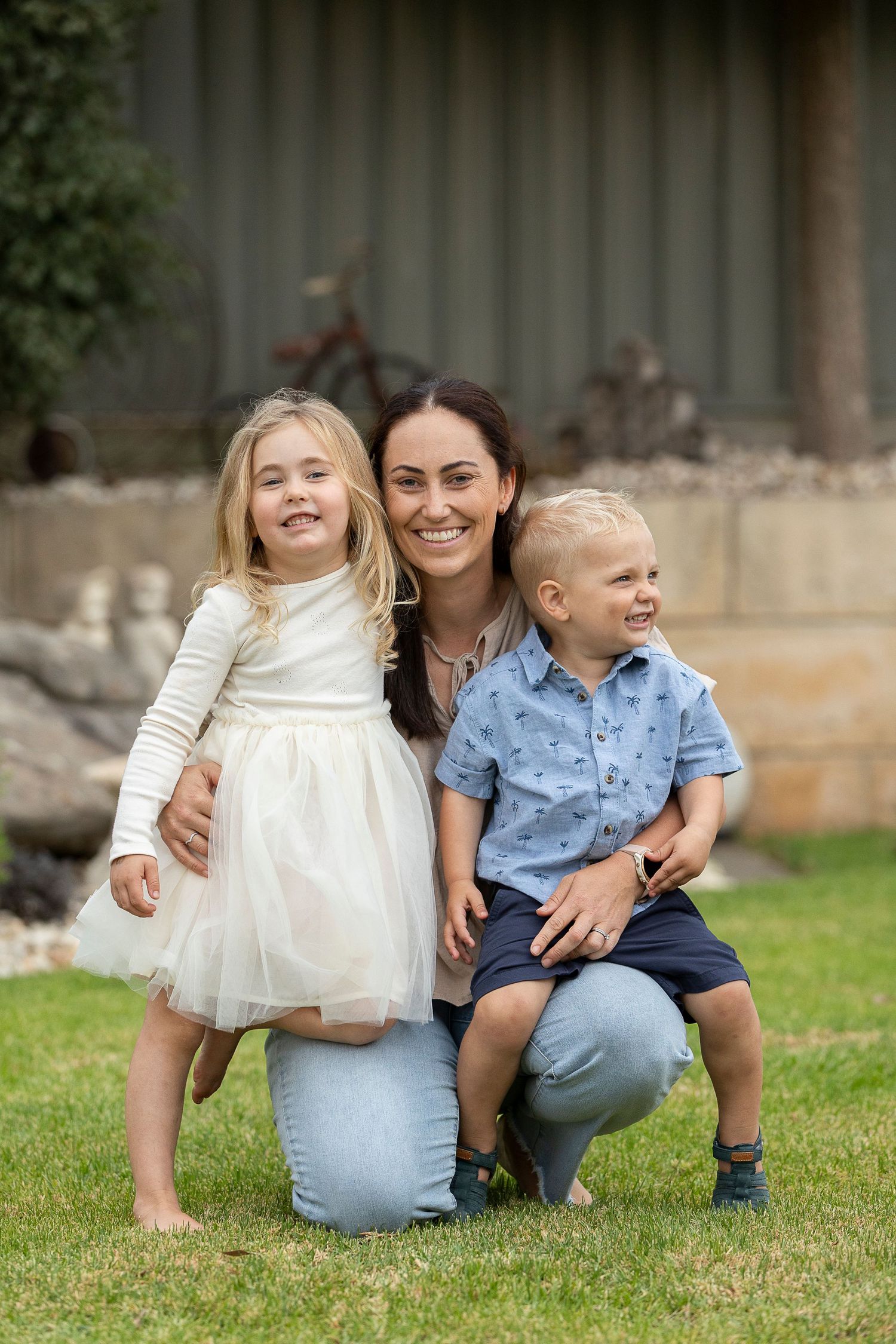 Children and adults share joyful moments while sitting on grass in coordinated outfits.