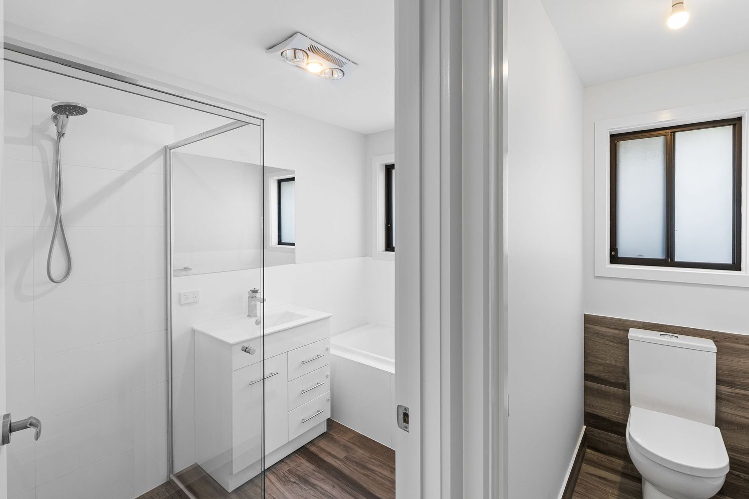 Sleek white hallway with modern lighting fixtures and hardwood flooring leads to multiple rooms.
