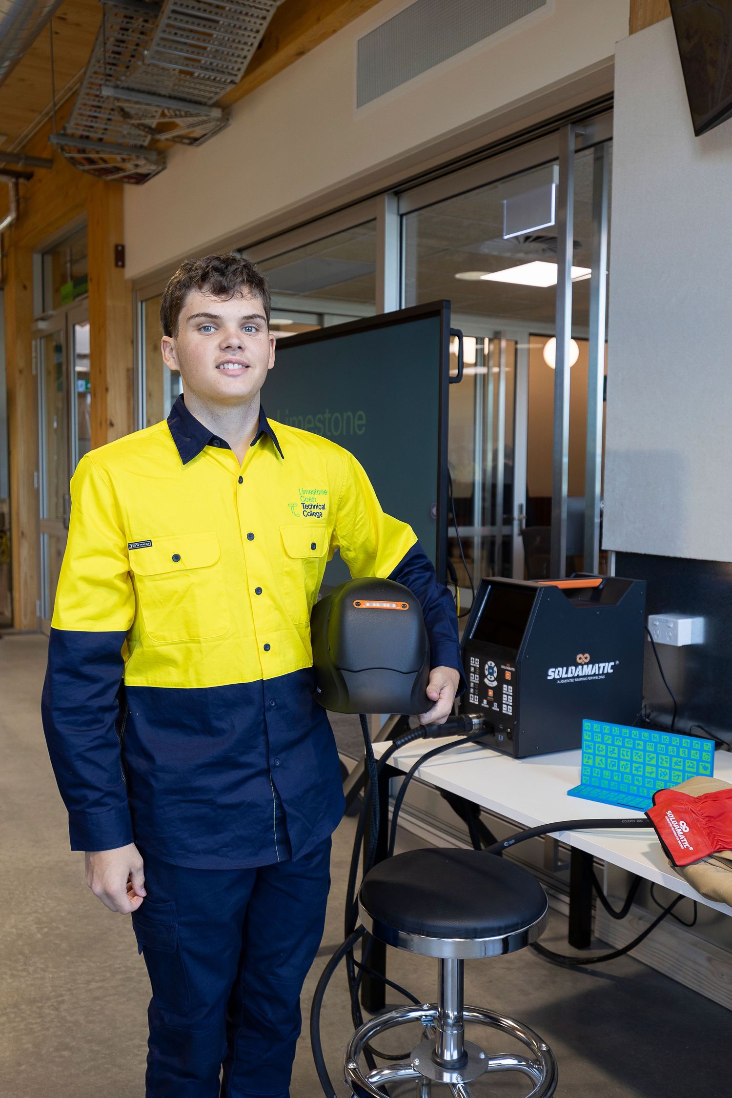 Person in safety workwear standing near office chairs and desks.