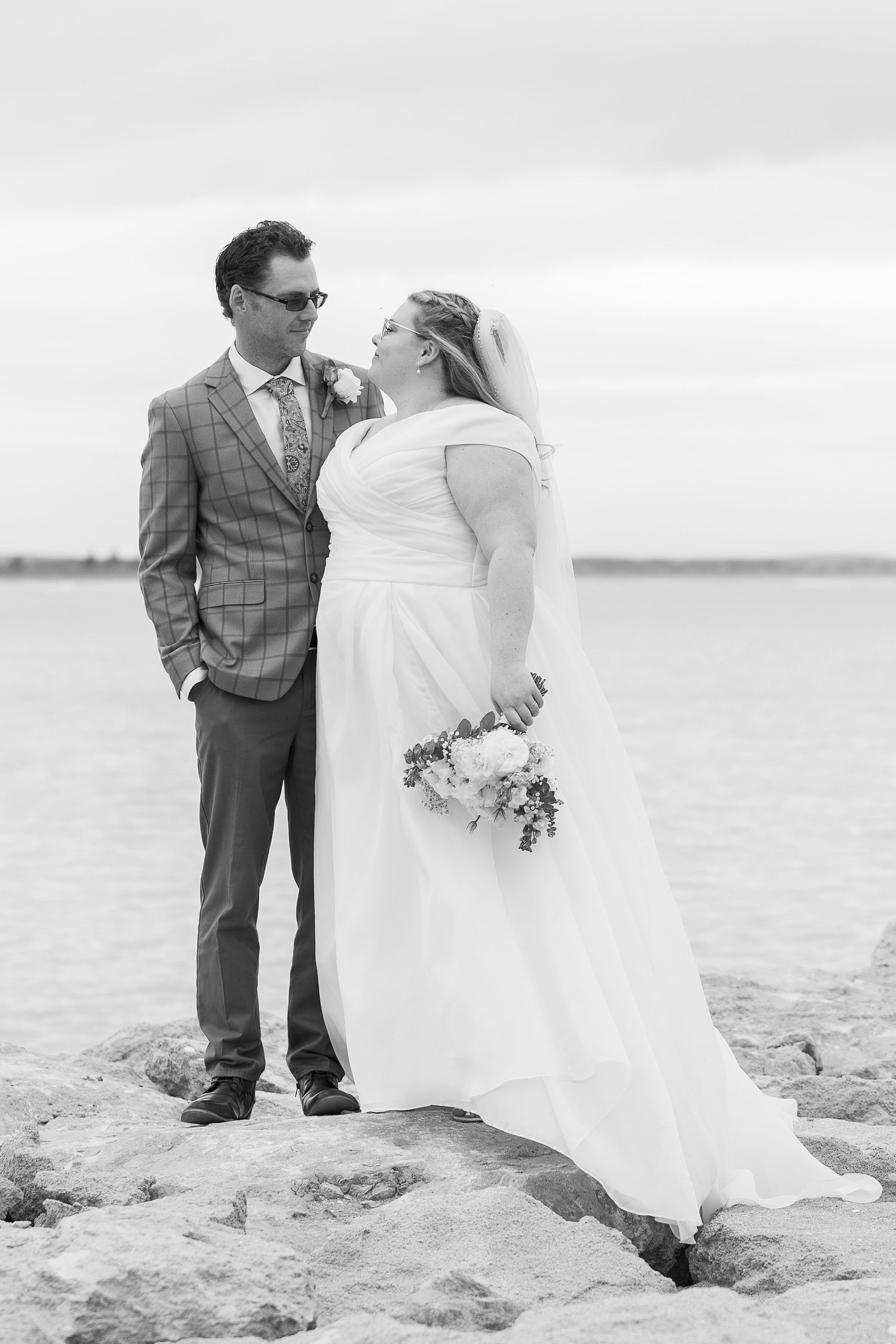 Black and white beach wedding portraits showing couple on sandy shoreline.