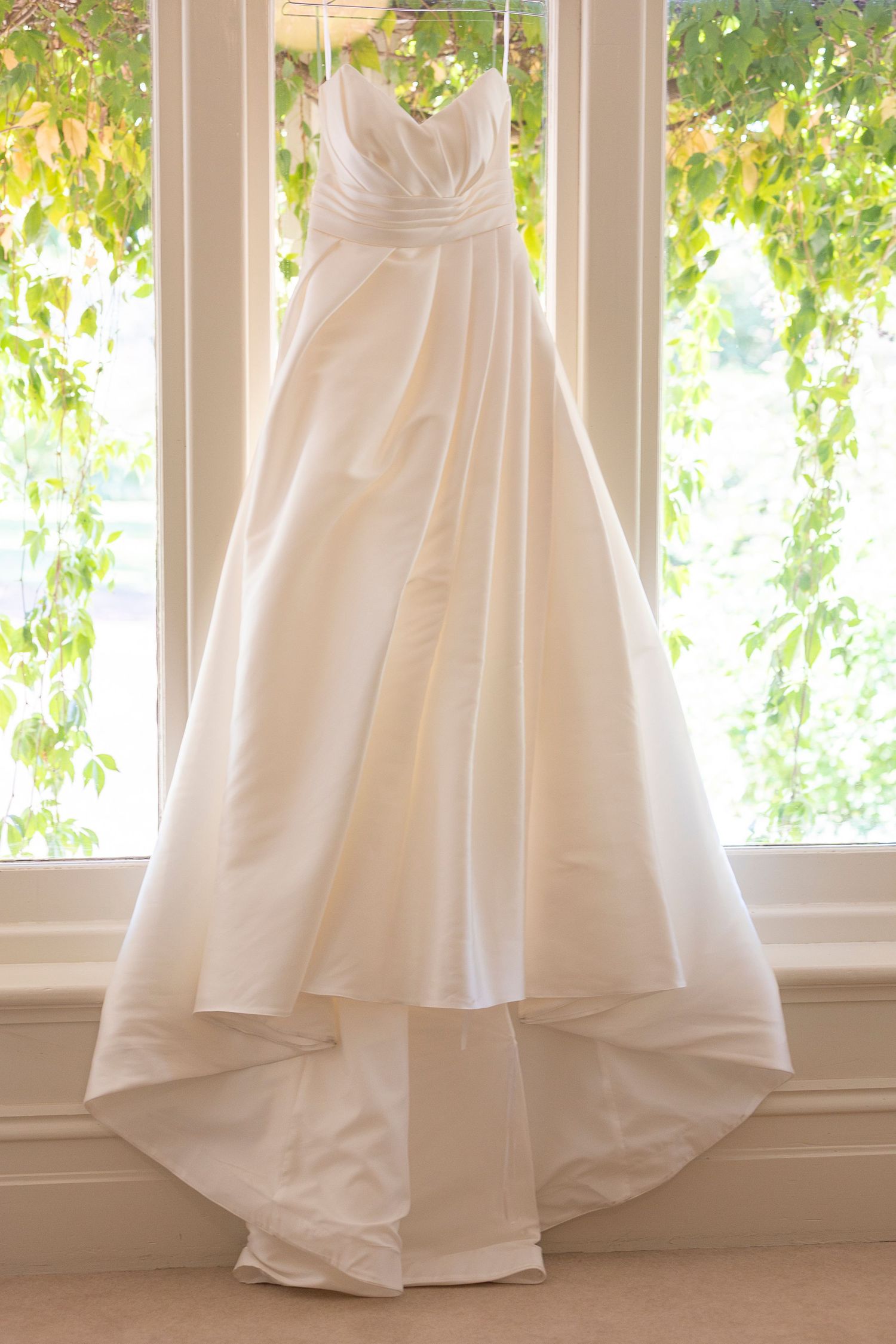 Close-up shots of a flowing white wedding dress hem against a sunlit window backdrop.