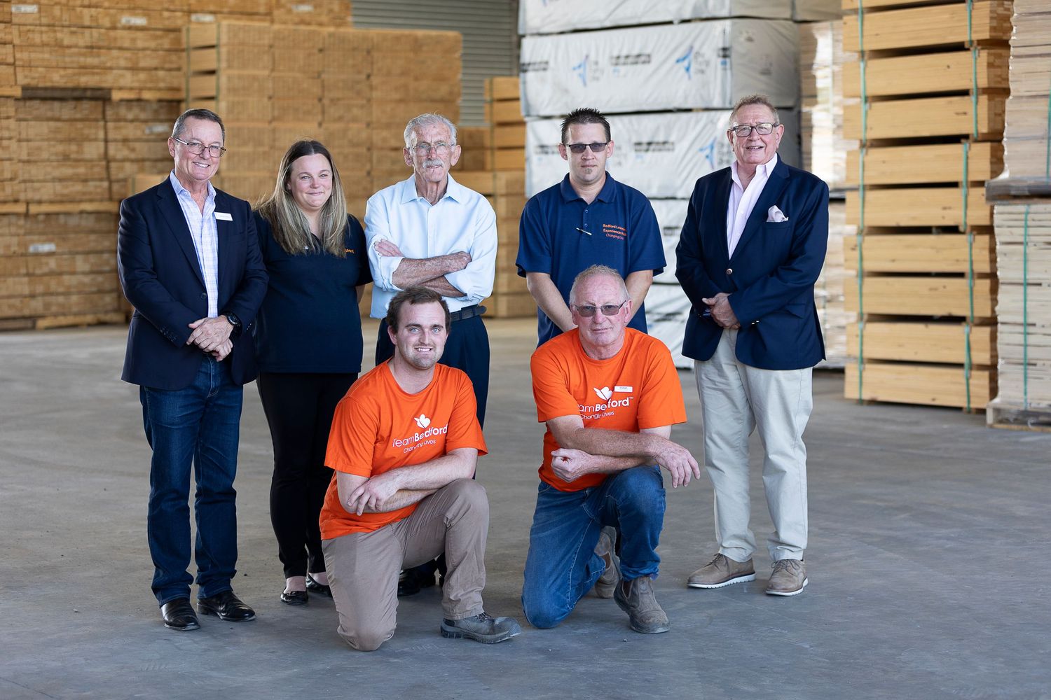 Team members gathered for a group photo in front of stacked wooden crates in a warehouse.