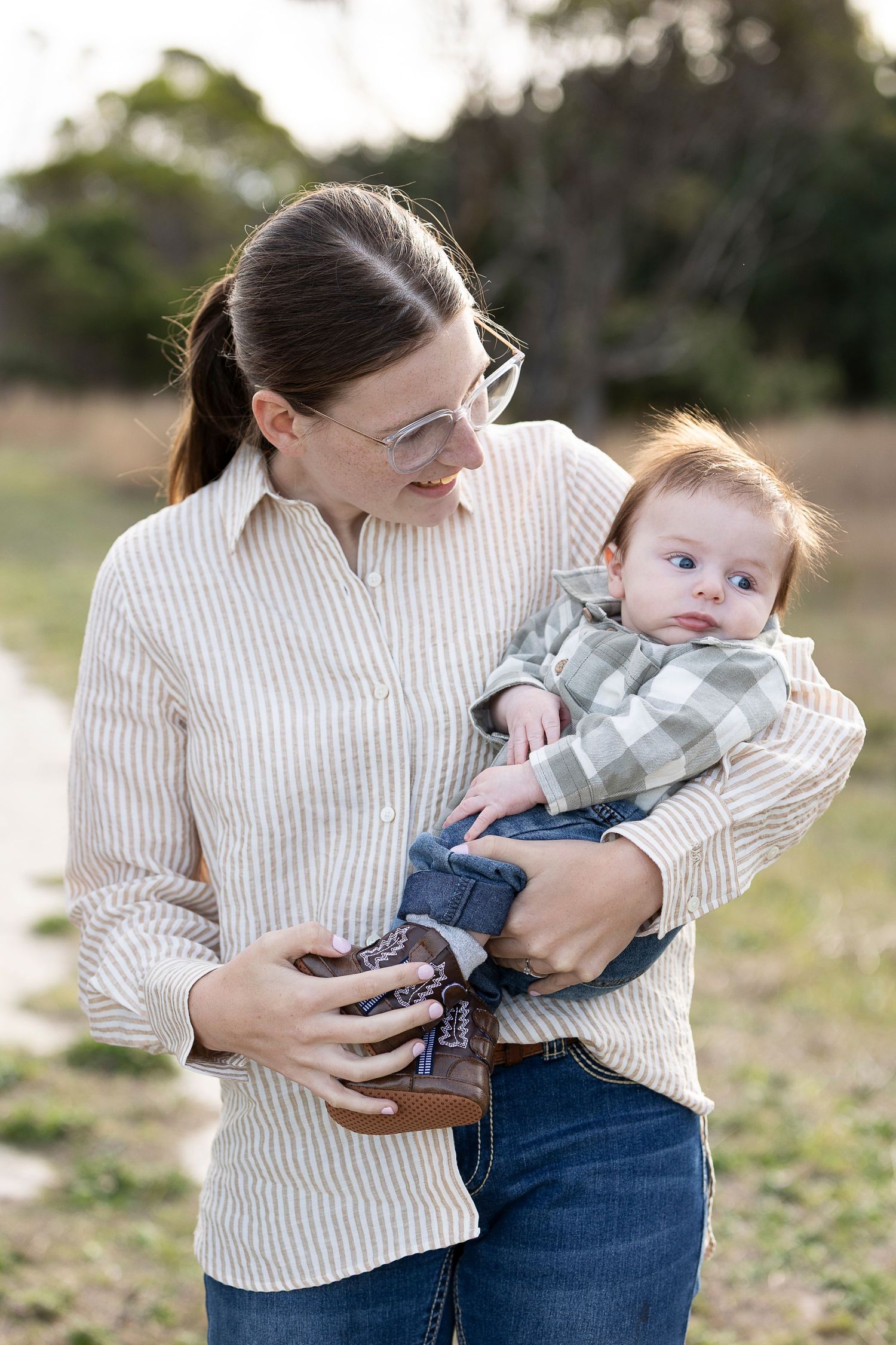Parent and baby sharing tender moment in matching striped shirts outdoors.