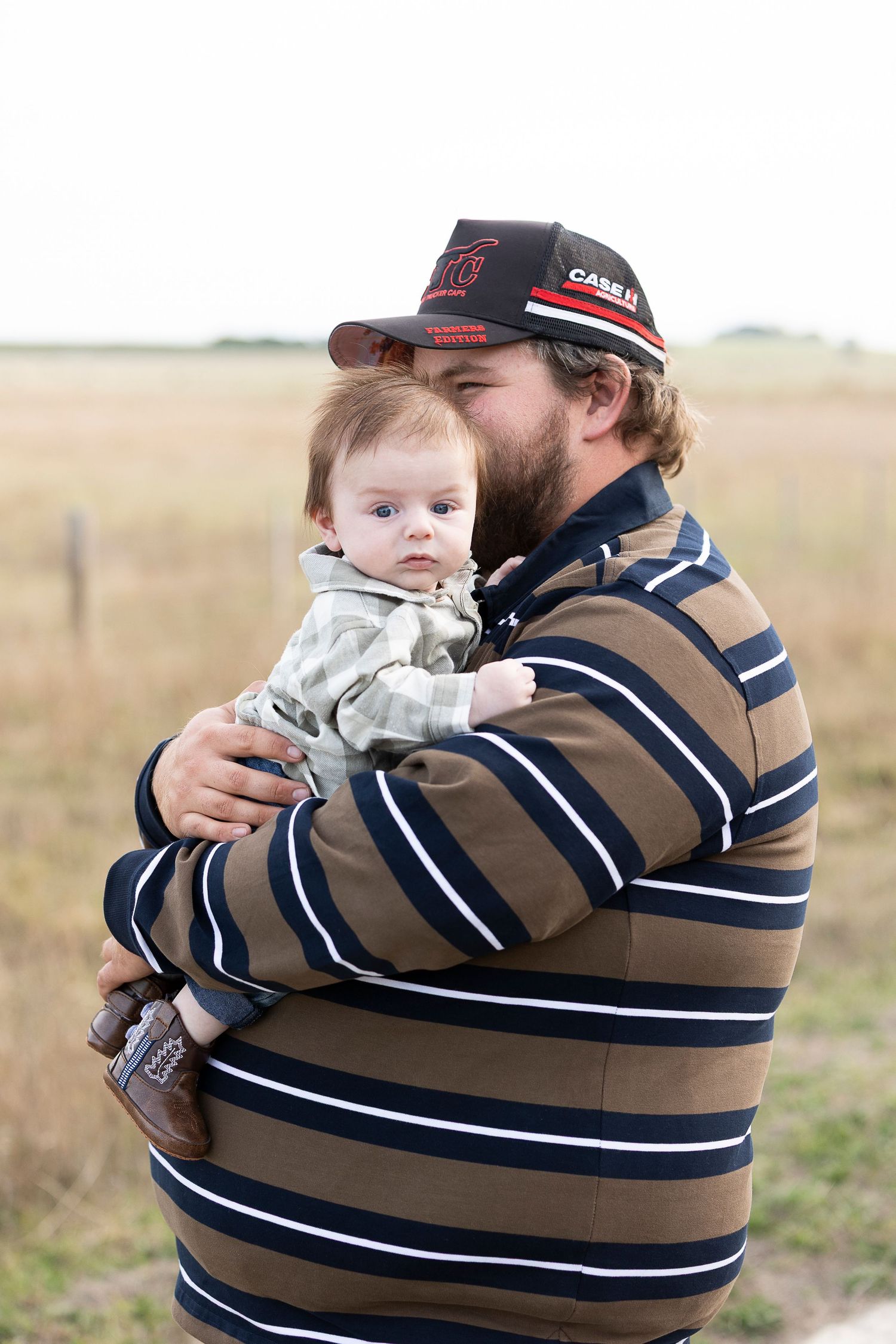 Person in striped sweater holding something while standing in an open field.