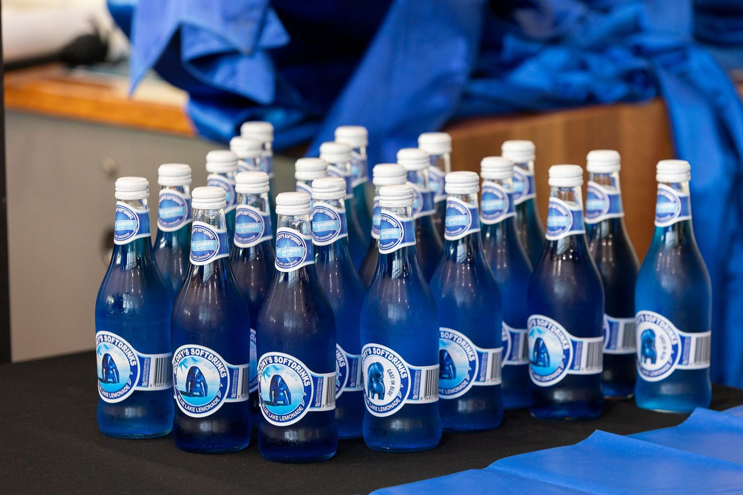Row of blue glass bottles arranged in a line on dark fabric.