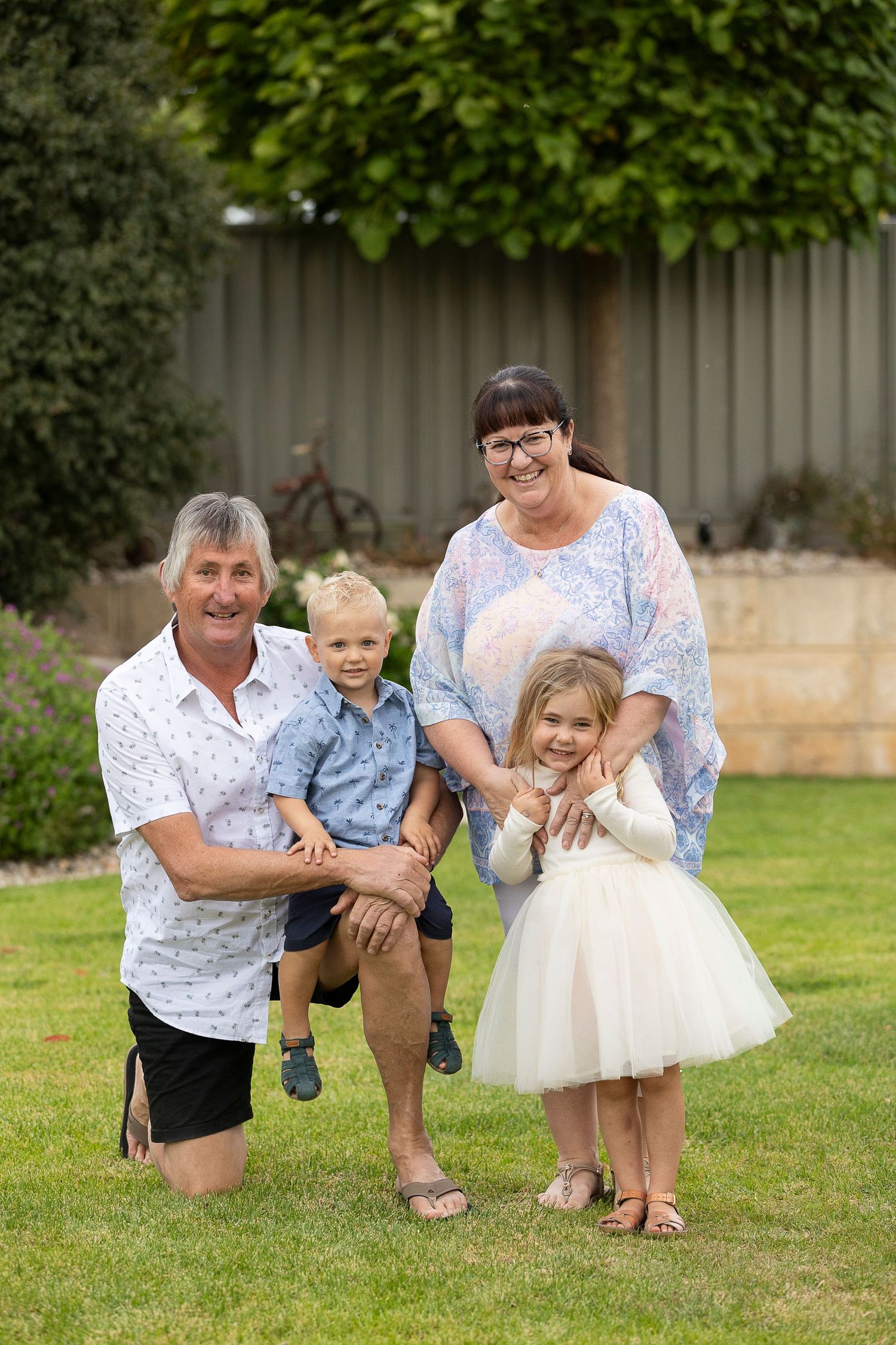 Playful family moments captured on grass with children in casual and dressy outfits.