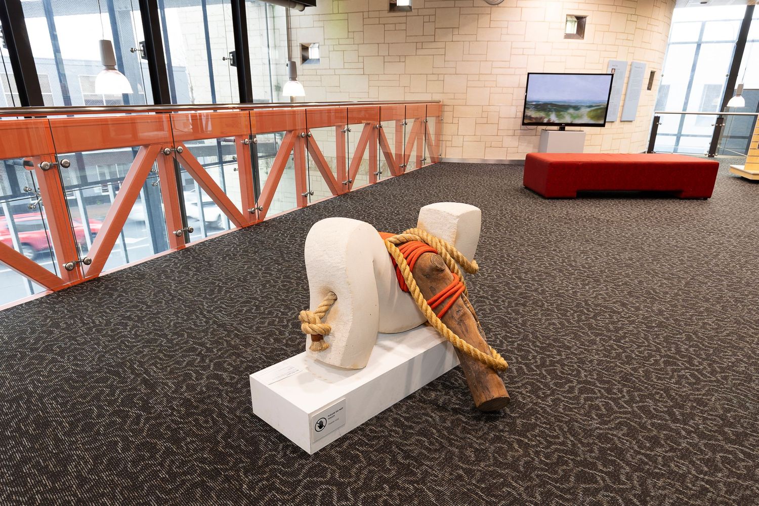 Art gallery exhibition space with white curved display tables and dark carpet flooring.
