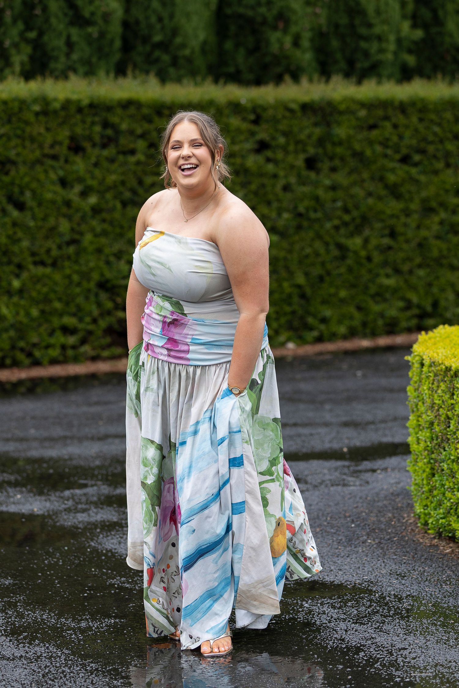 A flowing watercolor-style dress with blue and pink patterns photographed outdoors.