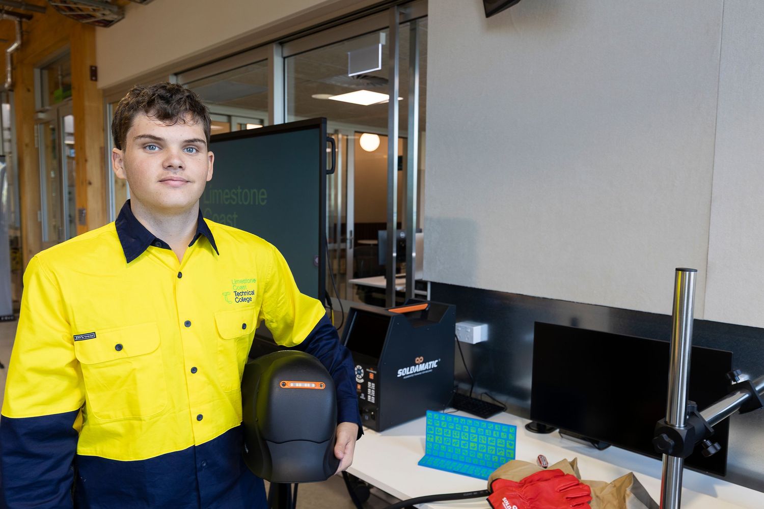 Professional wearing a high-visibility yellow and navy work uniform in an office setting.