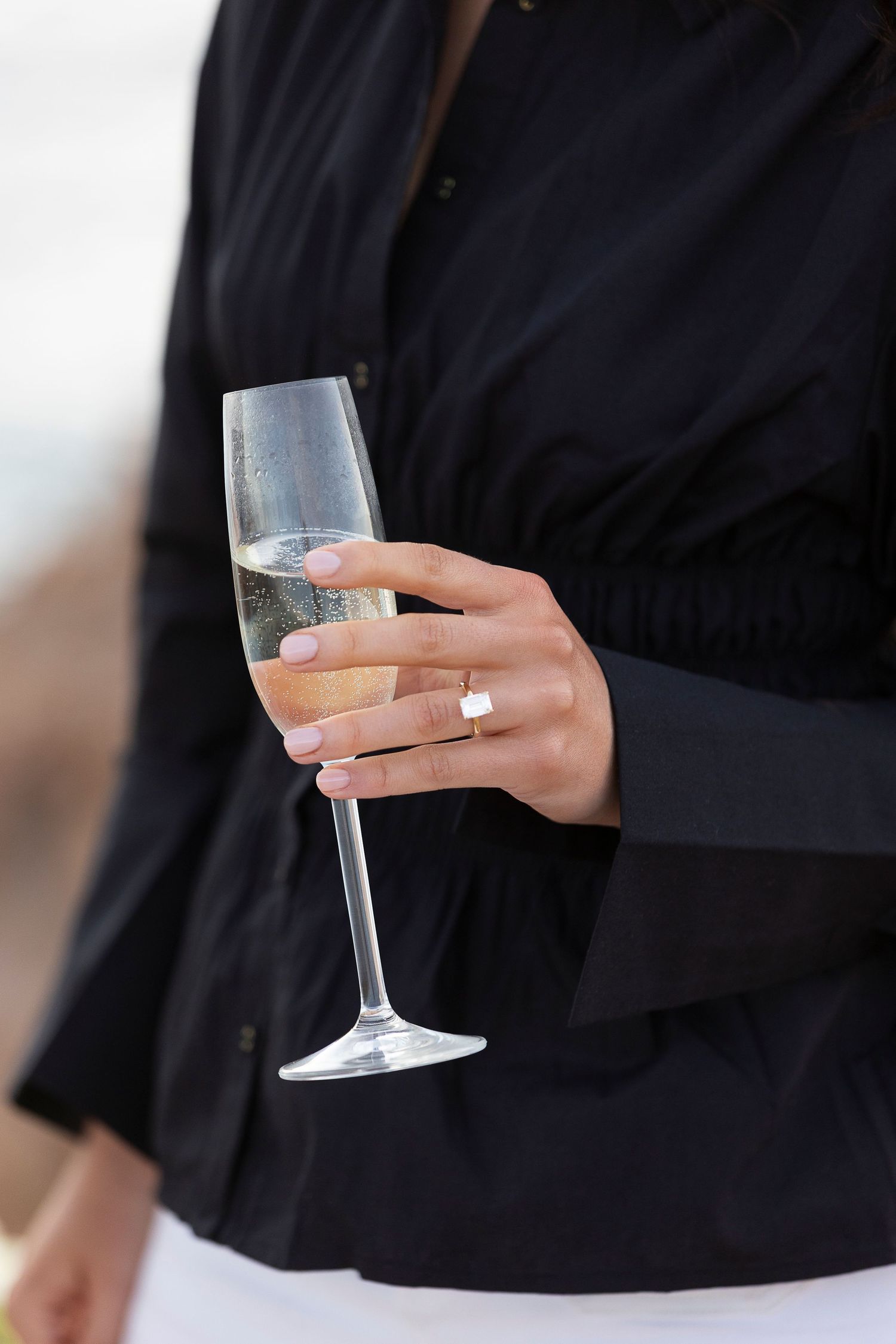 Close-up of hands holding champagne glasses in elegant wedding attire.