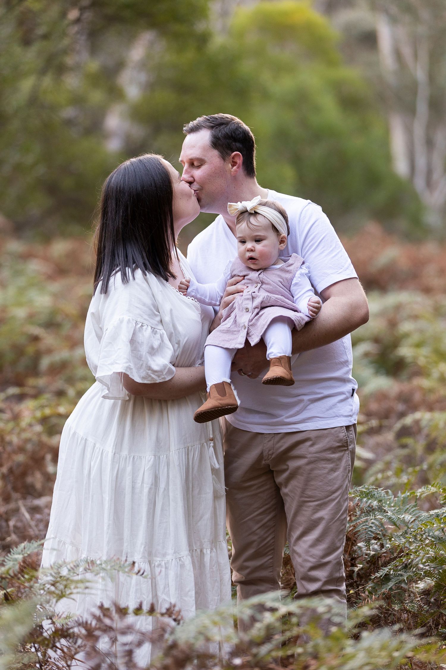 Couple embracing in a romantic moment among trees and foliage.