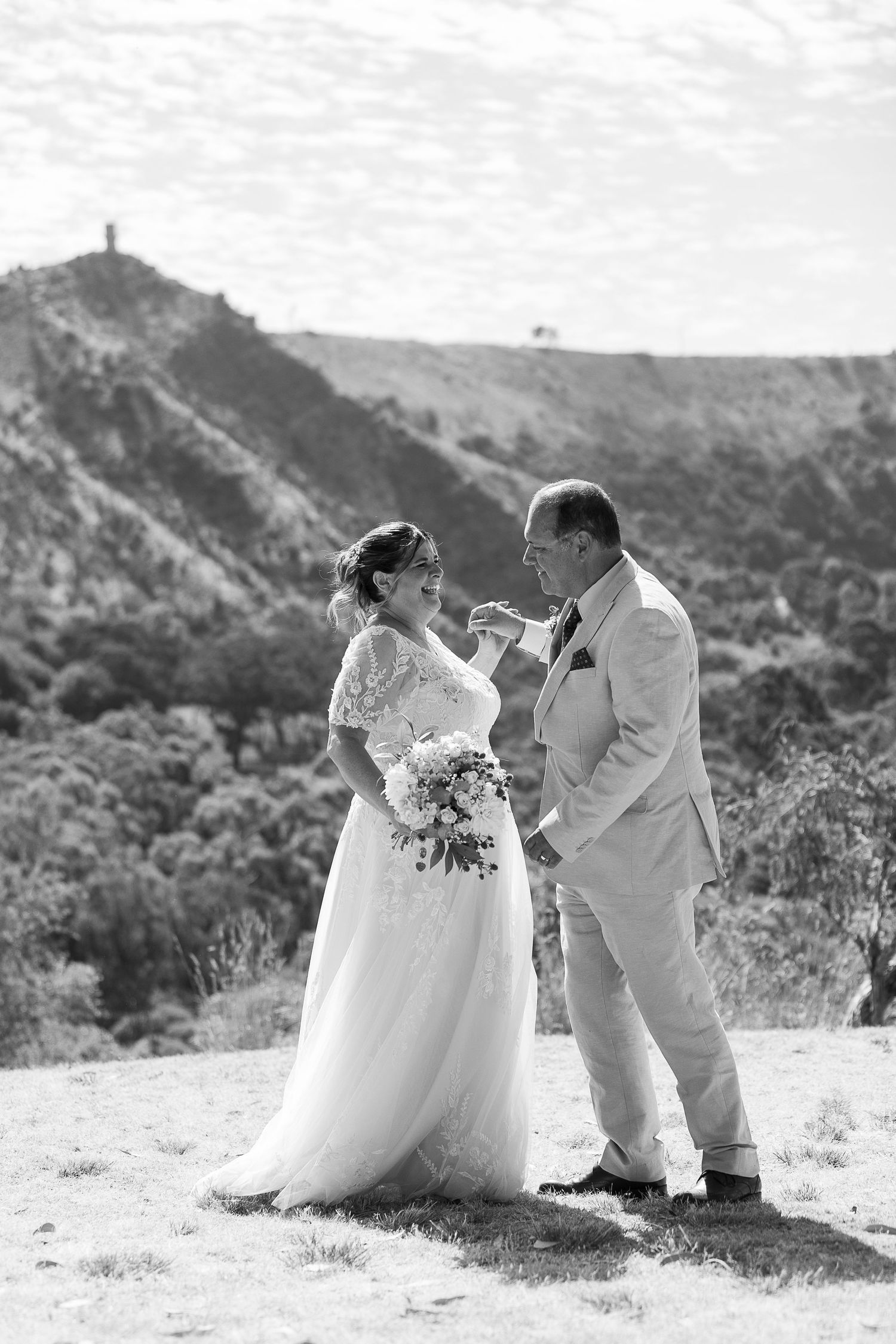 A romantic wedding photoshoot on a scenic mountainside with a flowing white dress and bouquet.