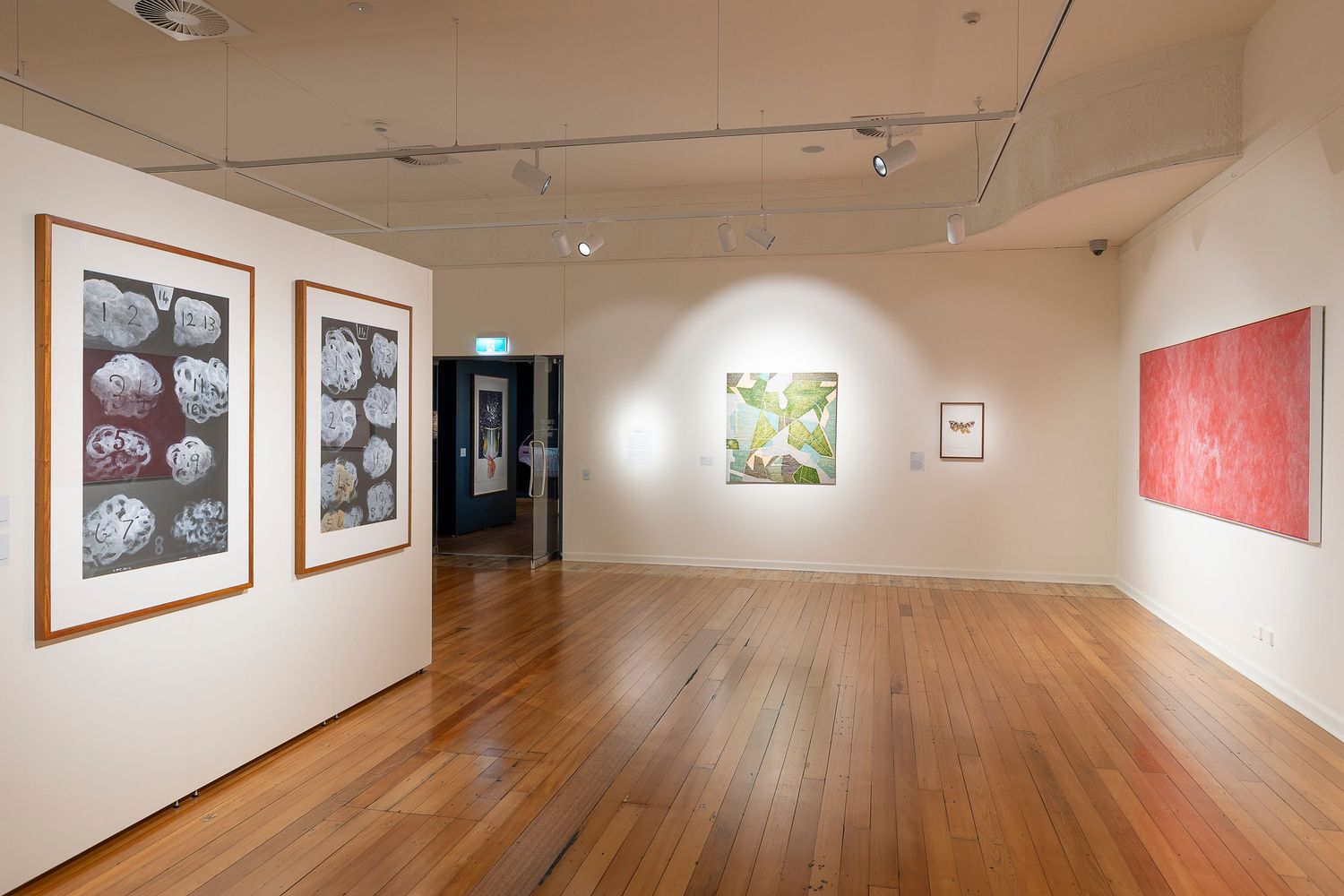Gallery interior with hardwood floors and white walls displaying framed photographs and artwork.