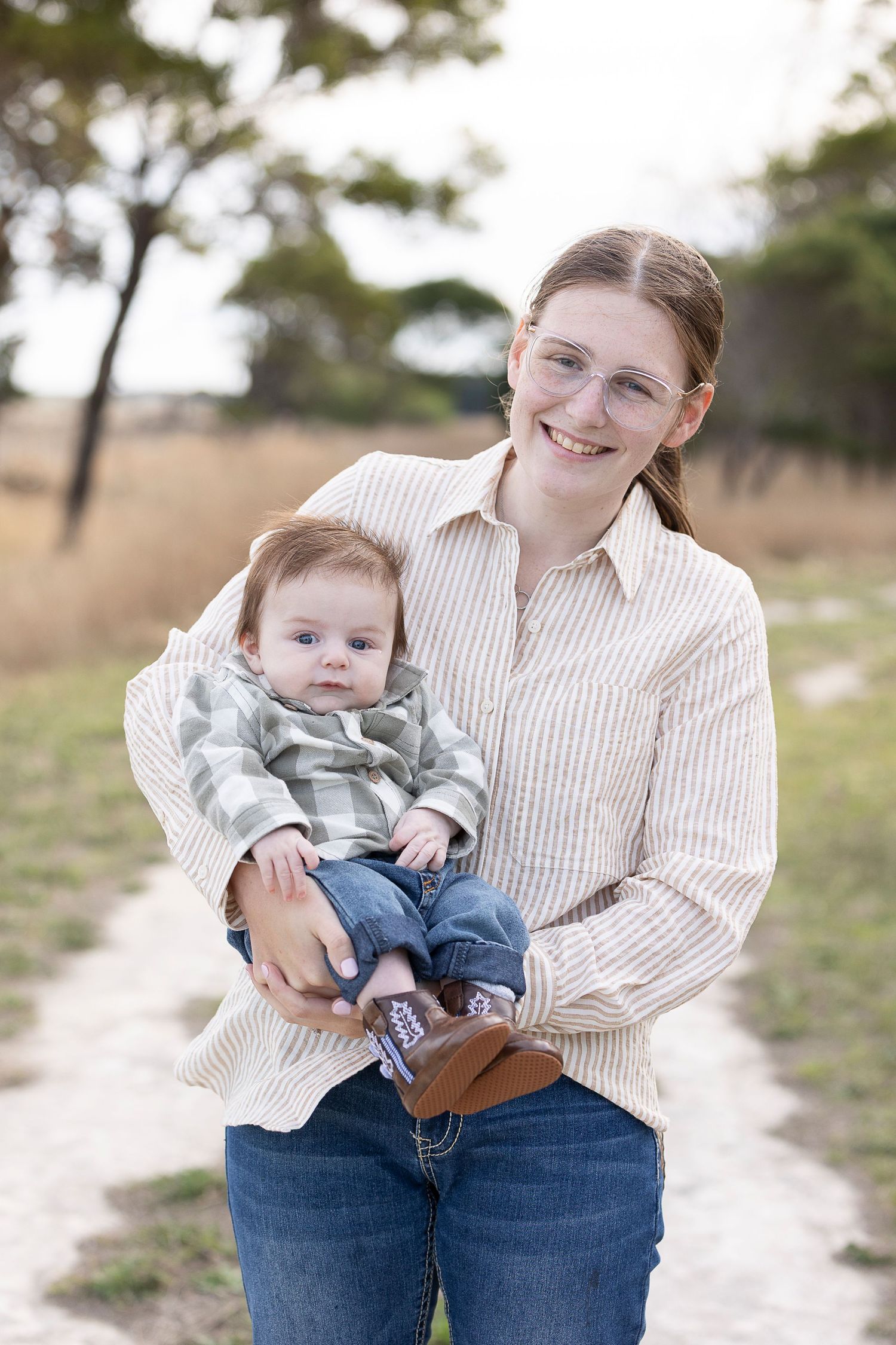 Parent and baby in coordinating striped shirts sharing playful moment outdoors.