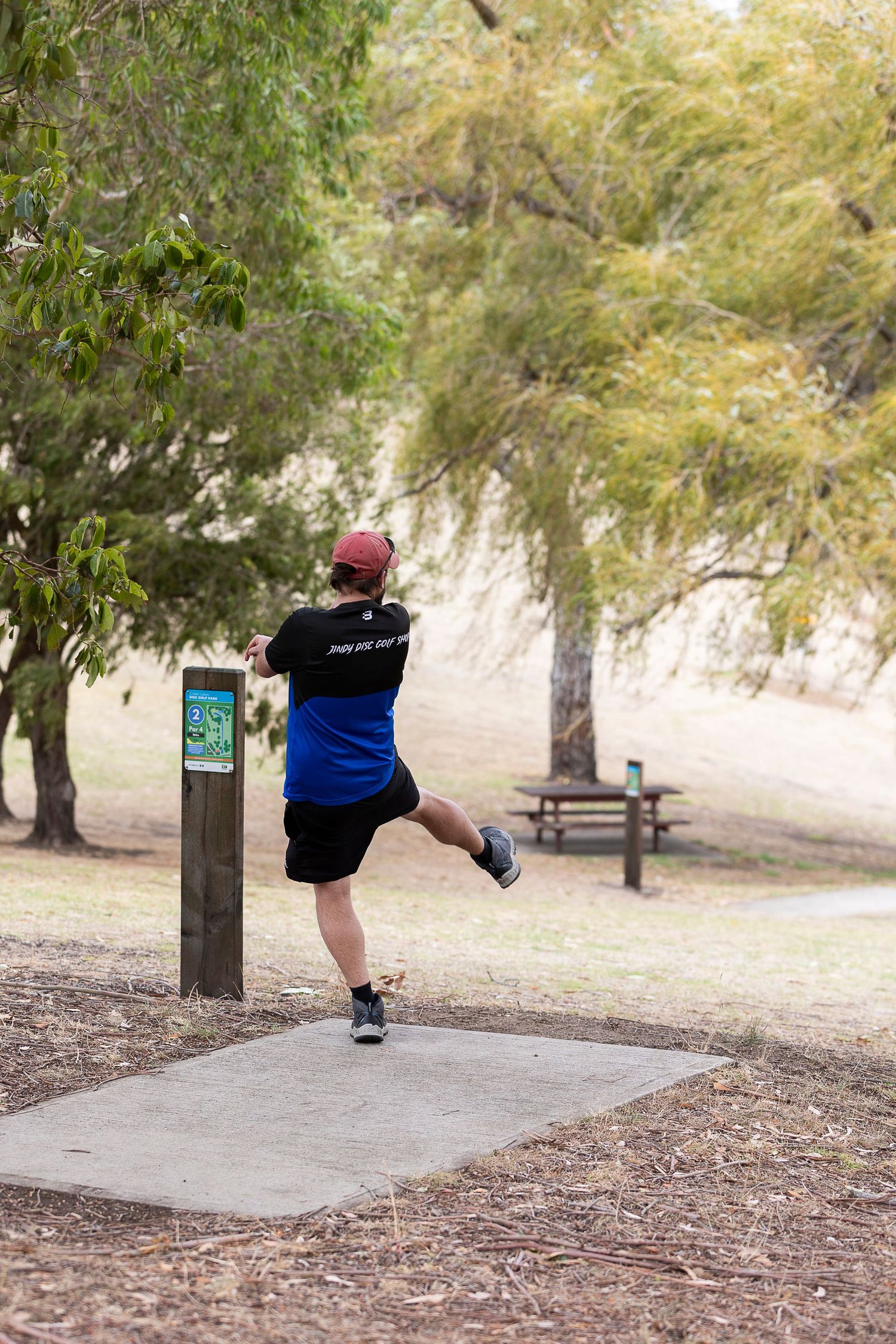 Person demonstrating exercise movements on outdoor fitness equipment in a park.