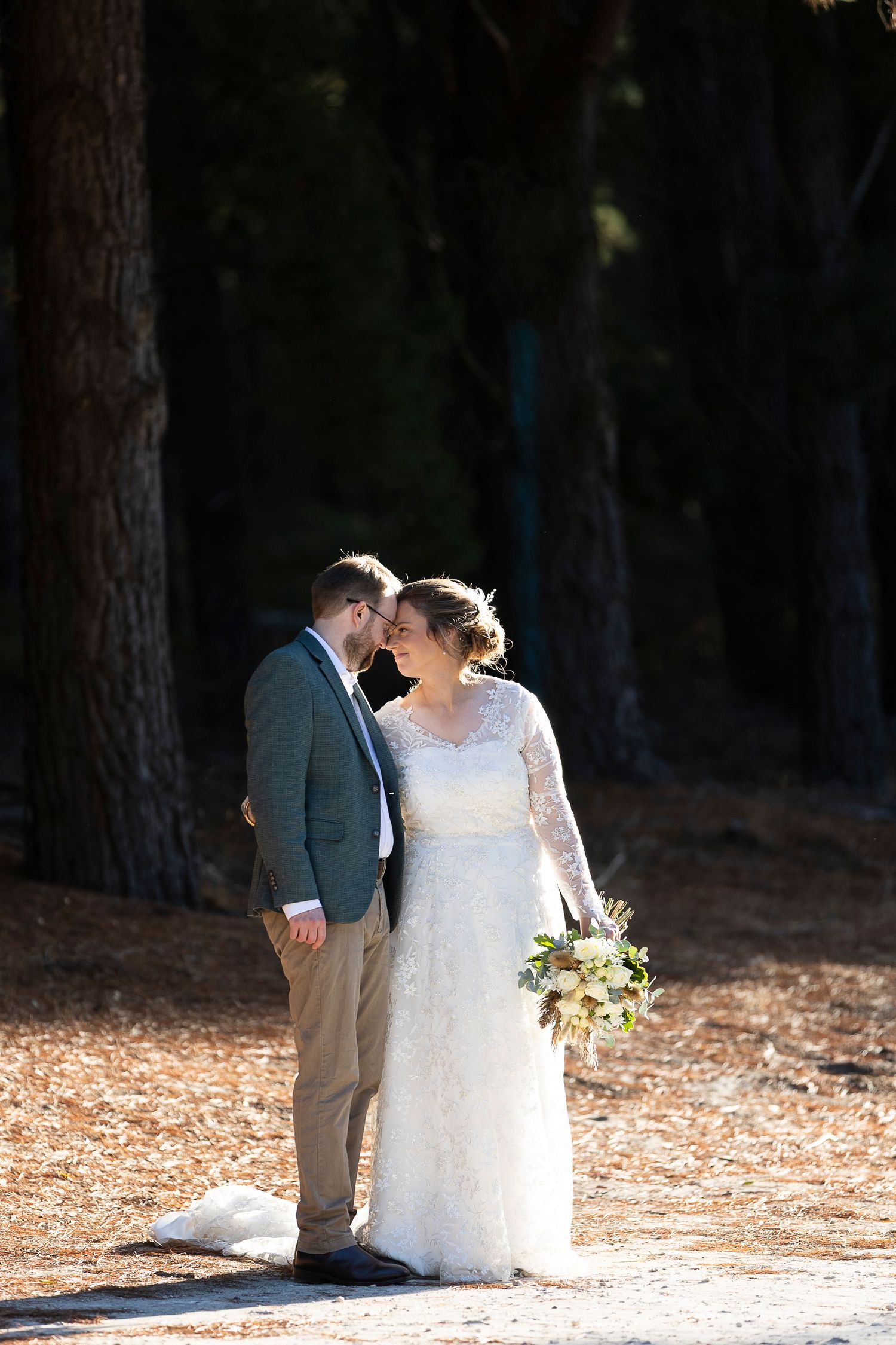 A romantic forest wedding photo session among tall pine trees with natural lighting.