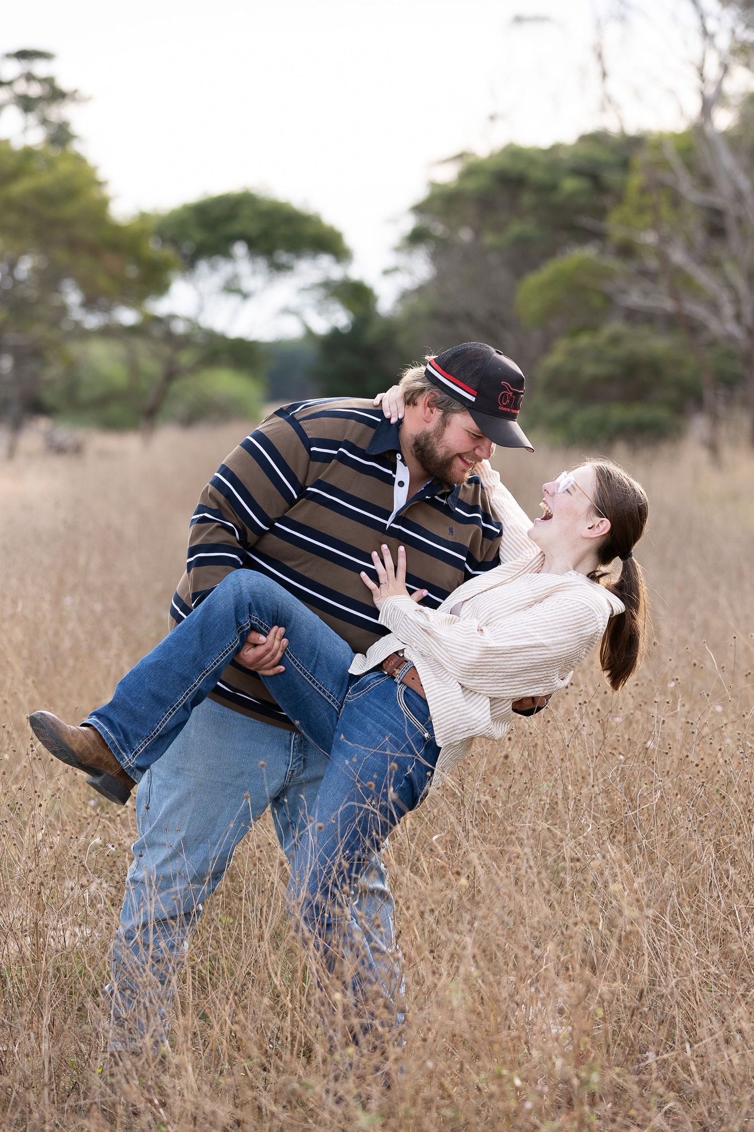 Playful couple dips in a golden field of tall grass.