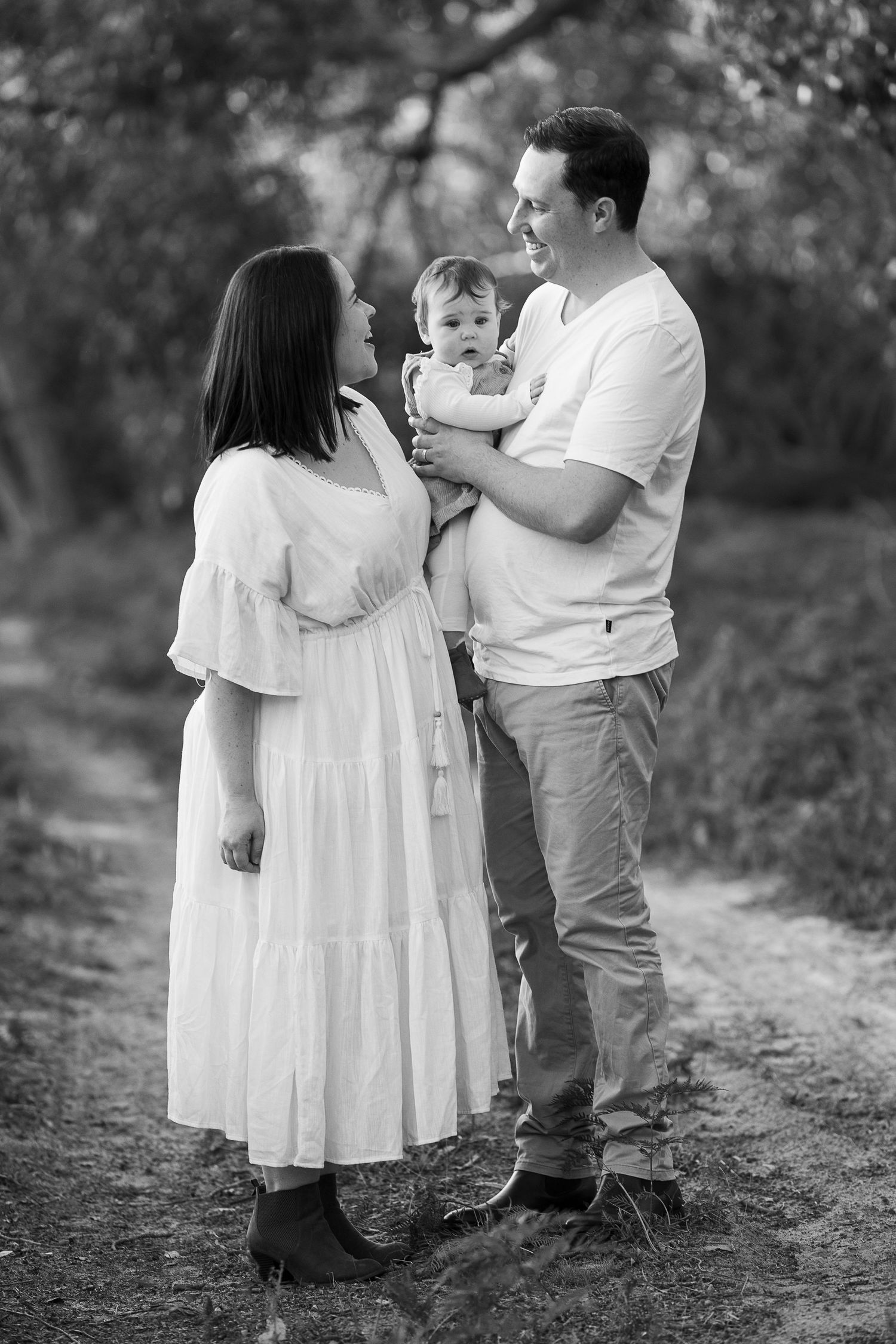 A family in white outfits posing together on a nature path.