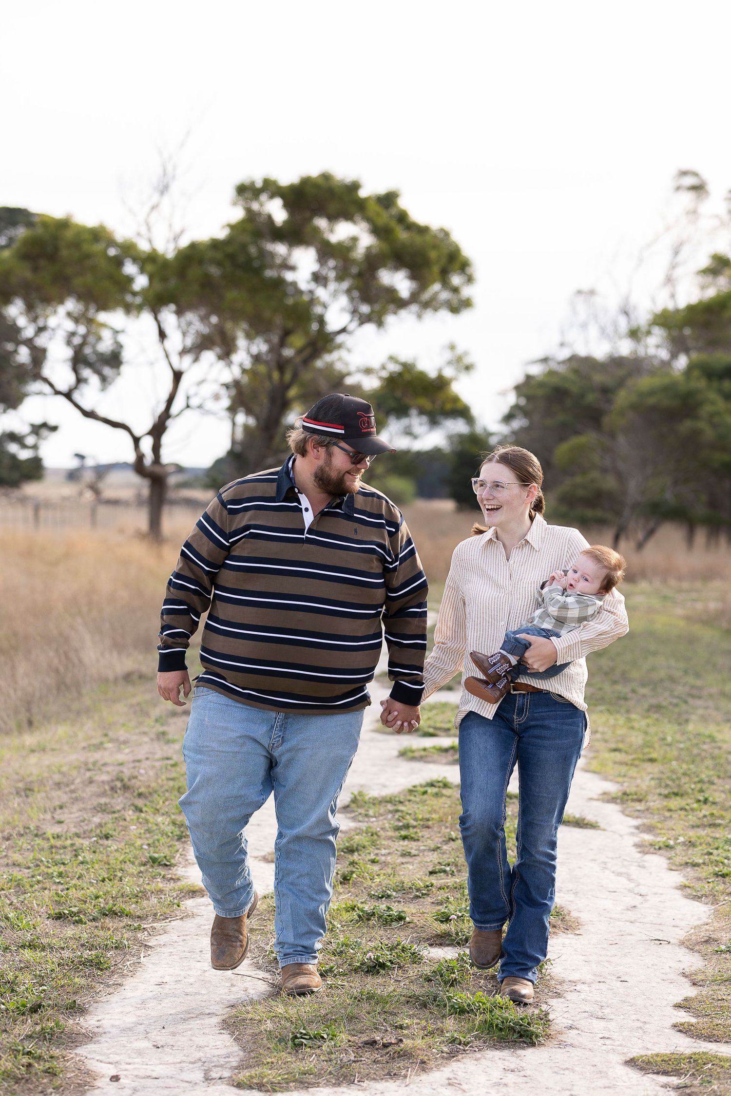 Family walking and playing together on sandy path through natural landscape.